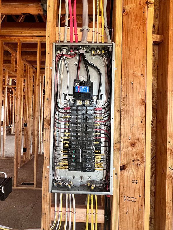 Open electrical circuit breaker panel in unfinished wooden house framing