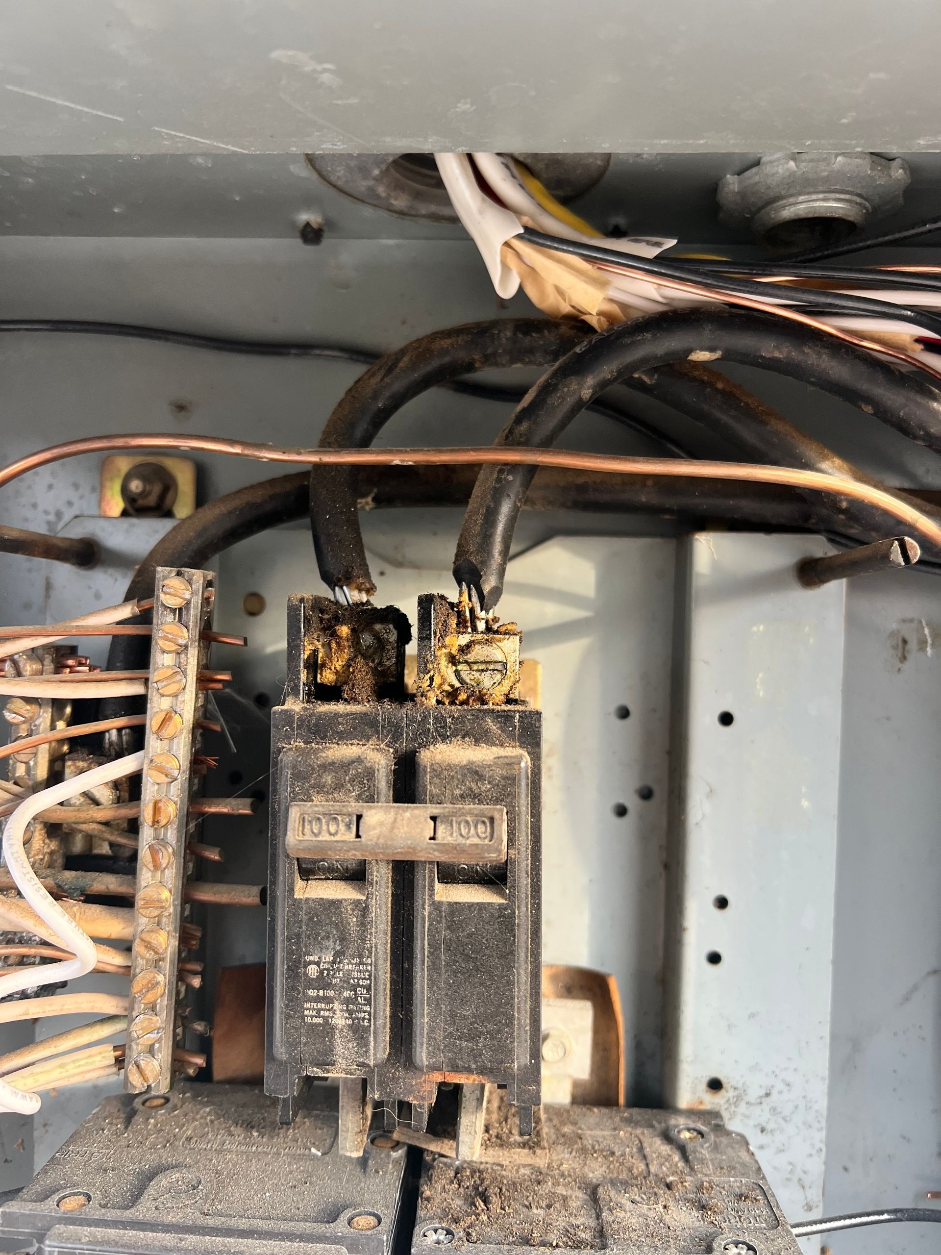 Close-up of a charred electrical breaker panel with melted wiring and soot damage.
