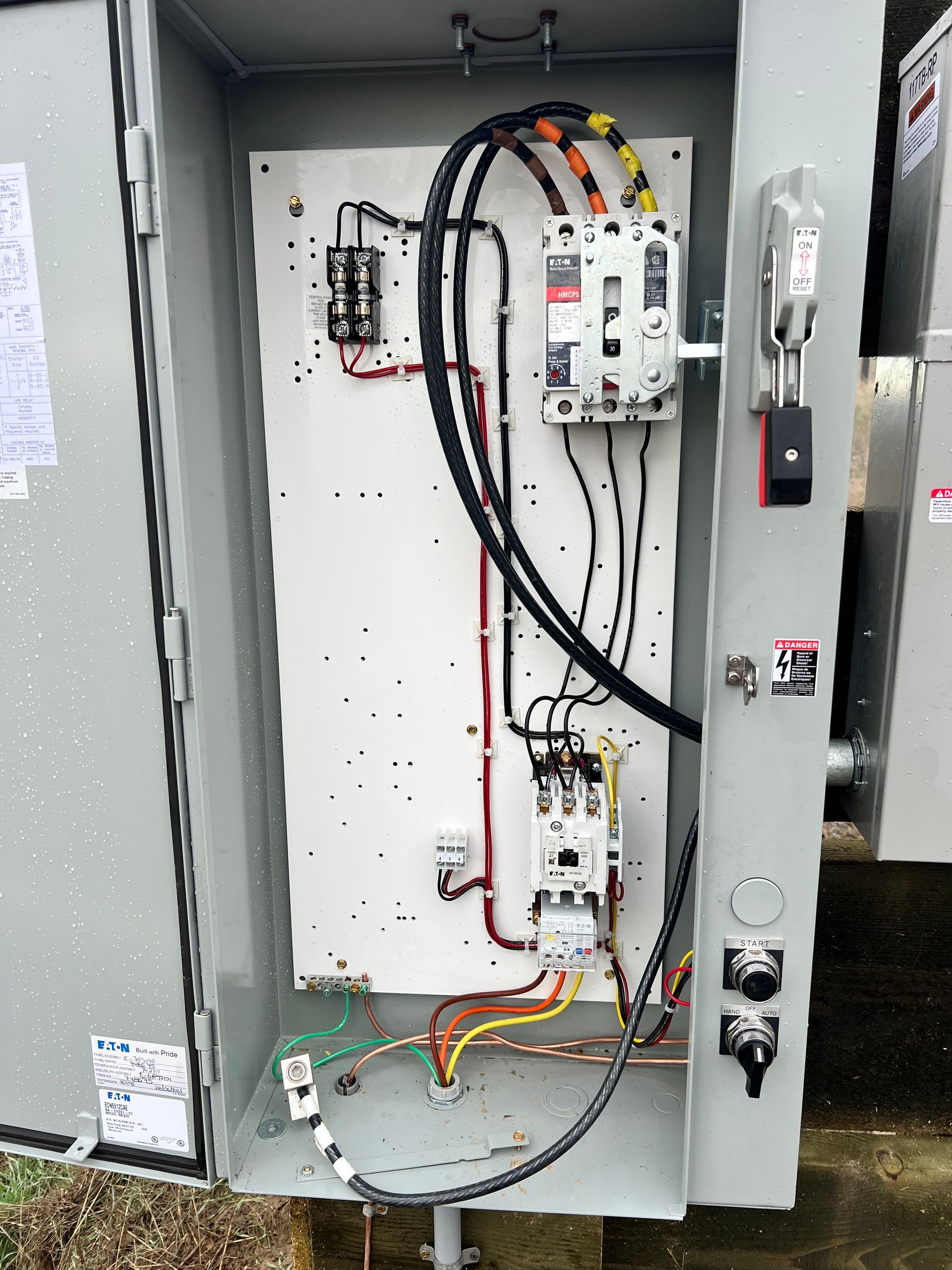 Open electrical control panel with wiring, breakers, and components inside a gray metal box