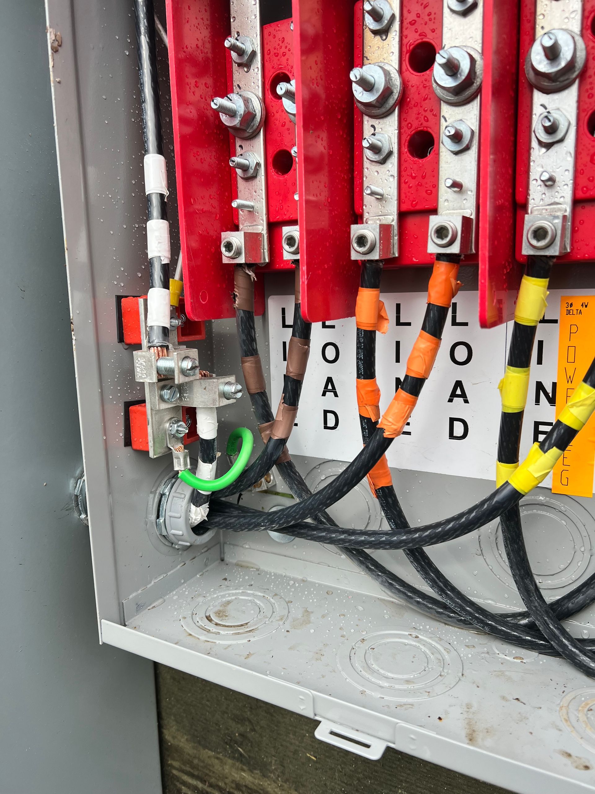 Close-up of electrical control panel with red components, black wires, and labeled wires inside a gray enclosure