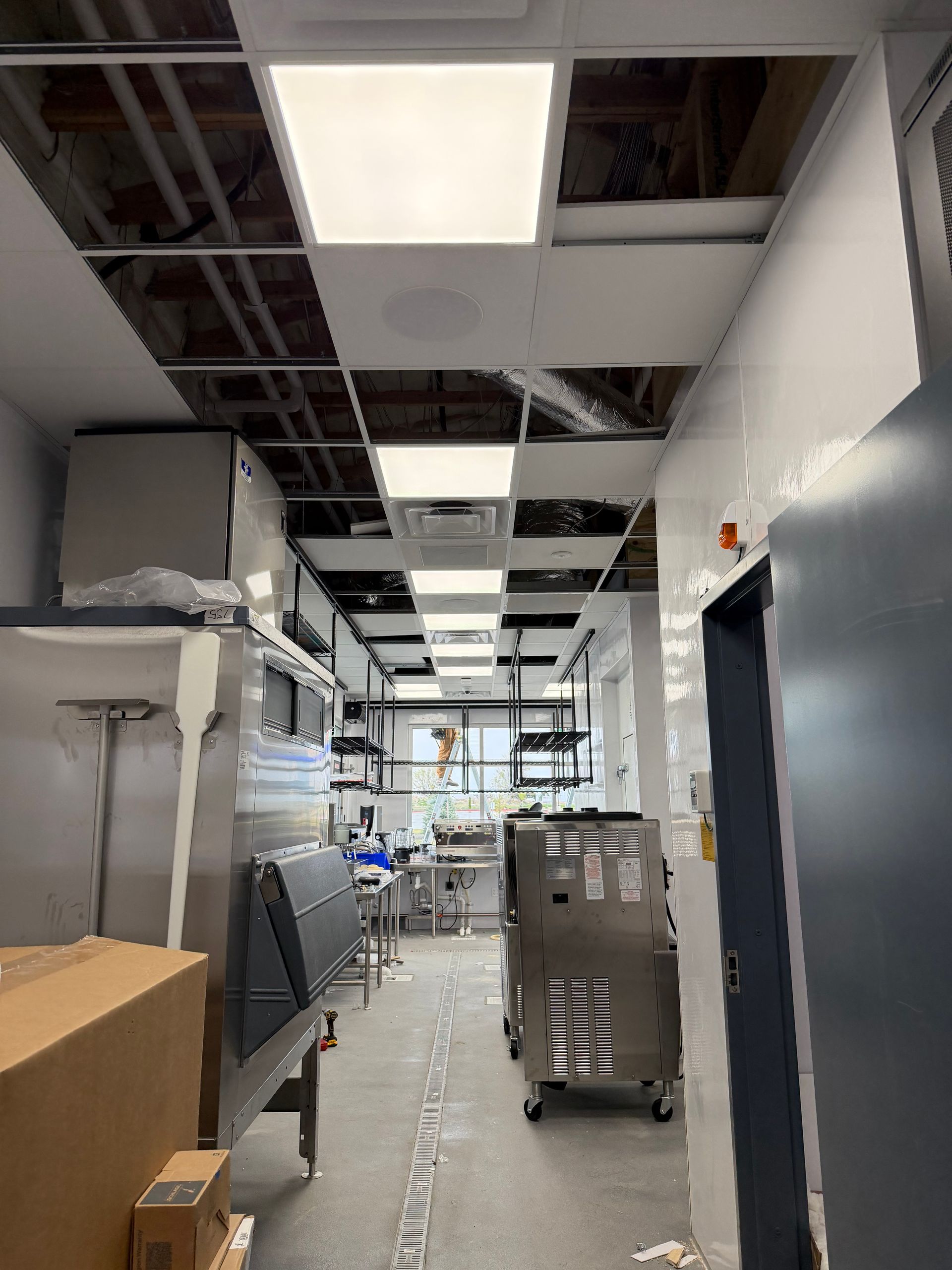 Industrial hallway with exposed ceiling, bright lights, and equipment carts along the corridor