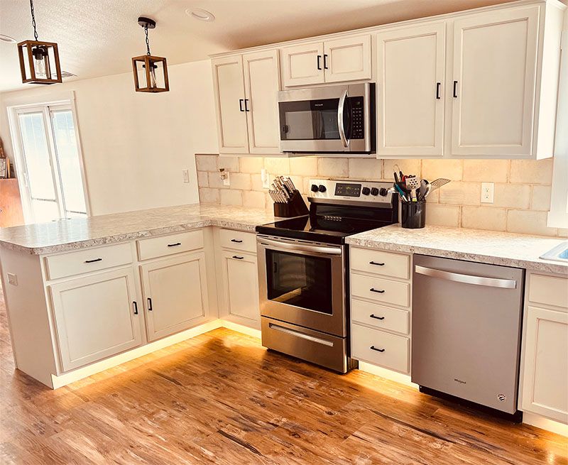 Bright modern kitchen with white cabinets, stainless steel appliances, granite counters, and wood floors