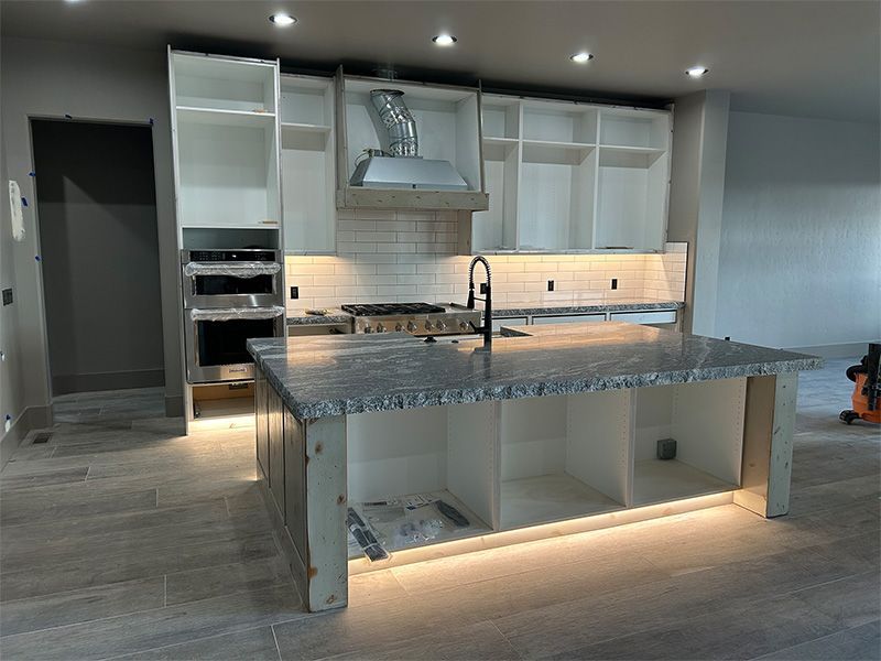 Modern kitchen with large island, white cabinetry, built-in oven, and under-cabinet lighting