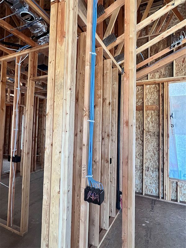 Exposed wooden framing inside a house under construction, with electrical wiring and unfinished walls.