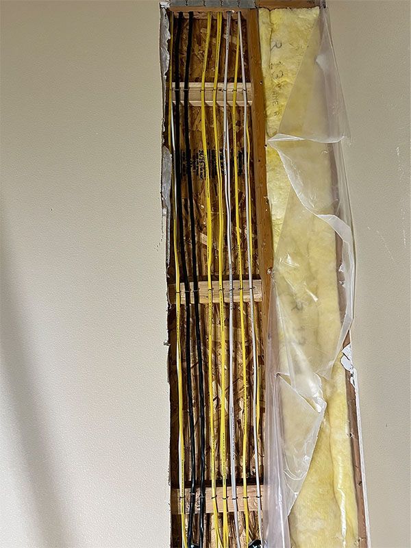Close-up of exposed electrical wiring and insulation inside a wall opening
