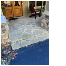 Stone porch with wooden double doors, a red chair, and blue driveway in front