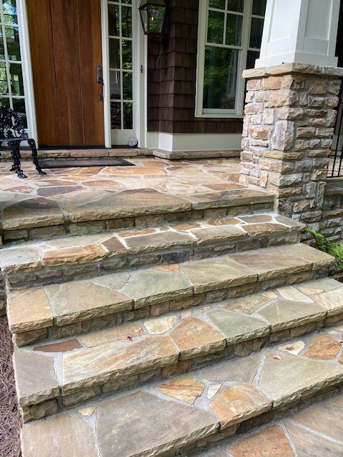 Stone front steps leading to a house entrance with wooden door and windows.