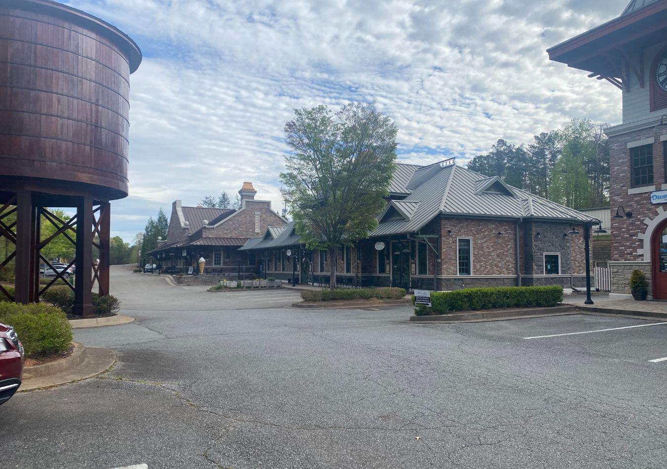 Gravel courtyard with rustic buildings and a large wooden water tower under a cloudy sky