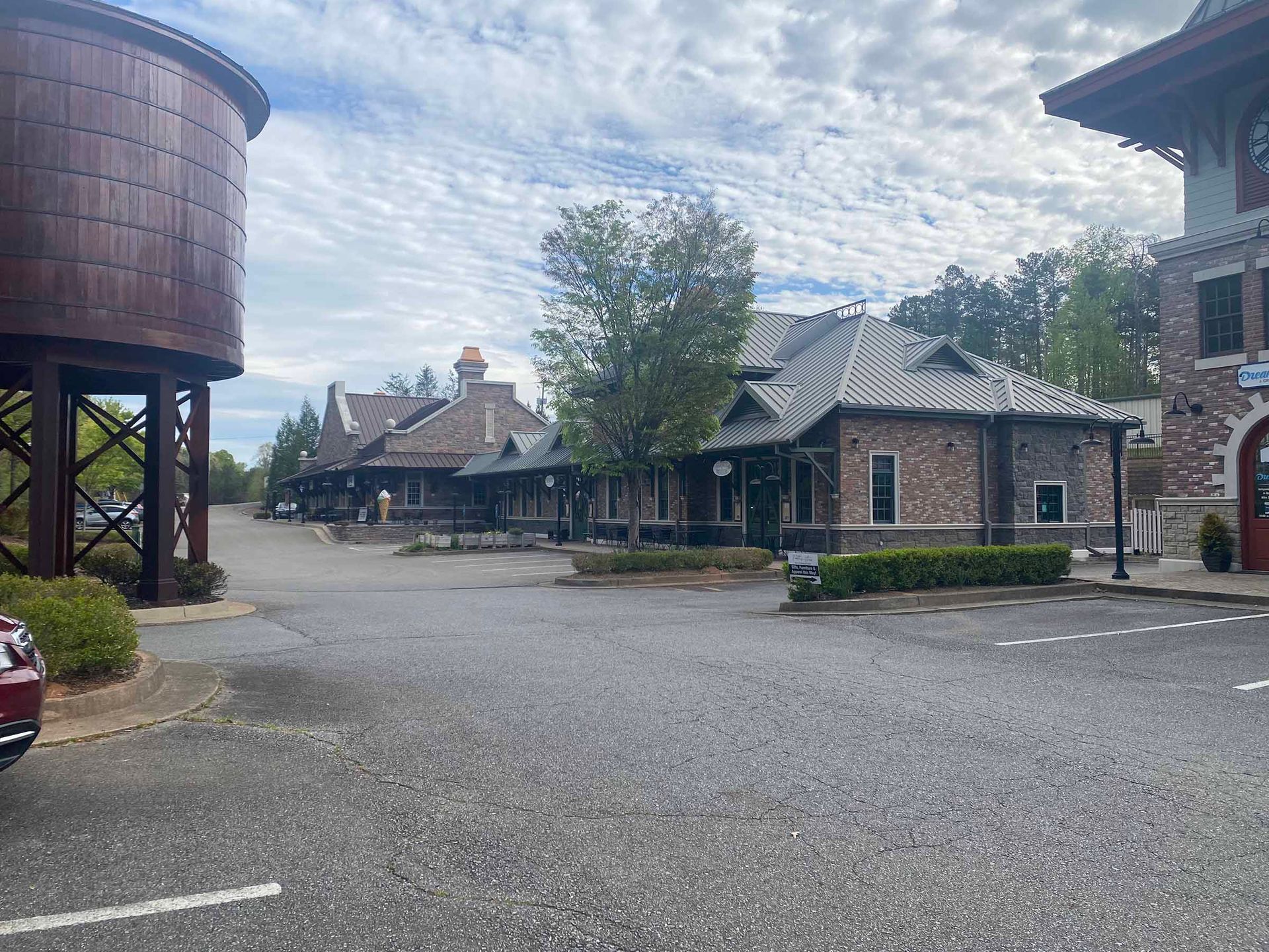 Gravel courtyard with brick buildings, a water tower, and a cloudy sky