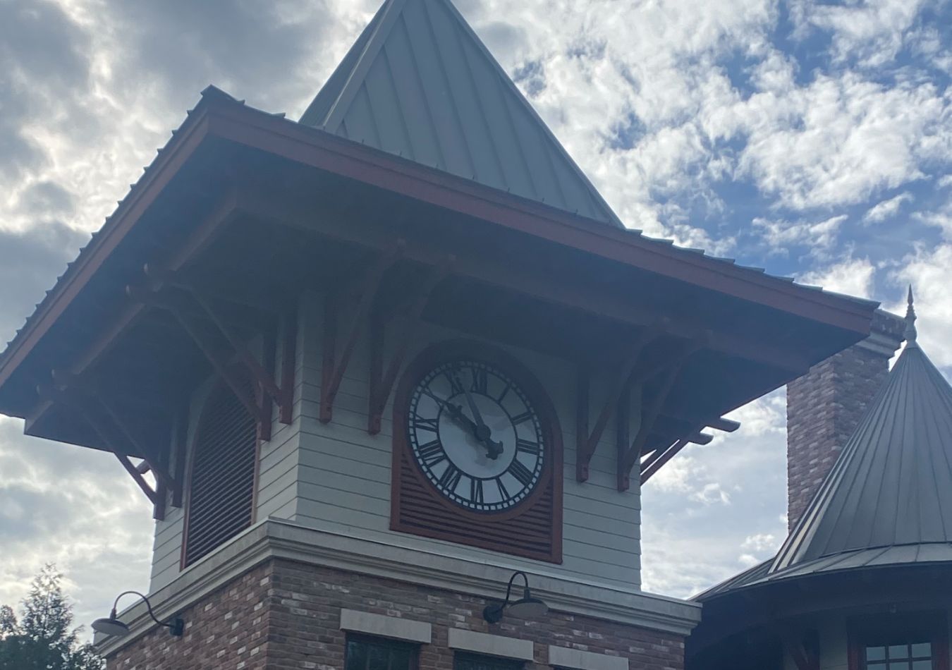Clock tower with a steep roof and brick facade against a cloudy sky