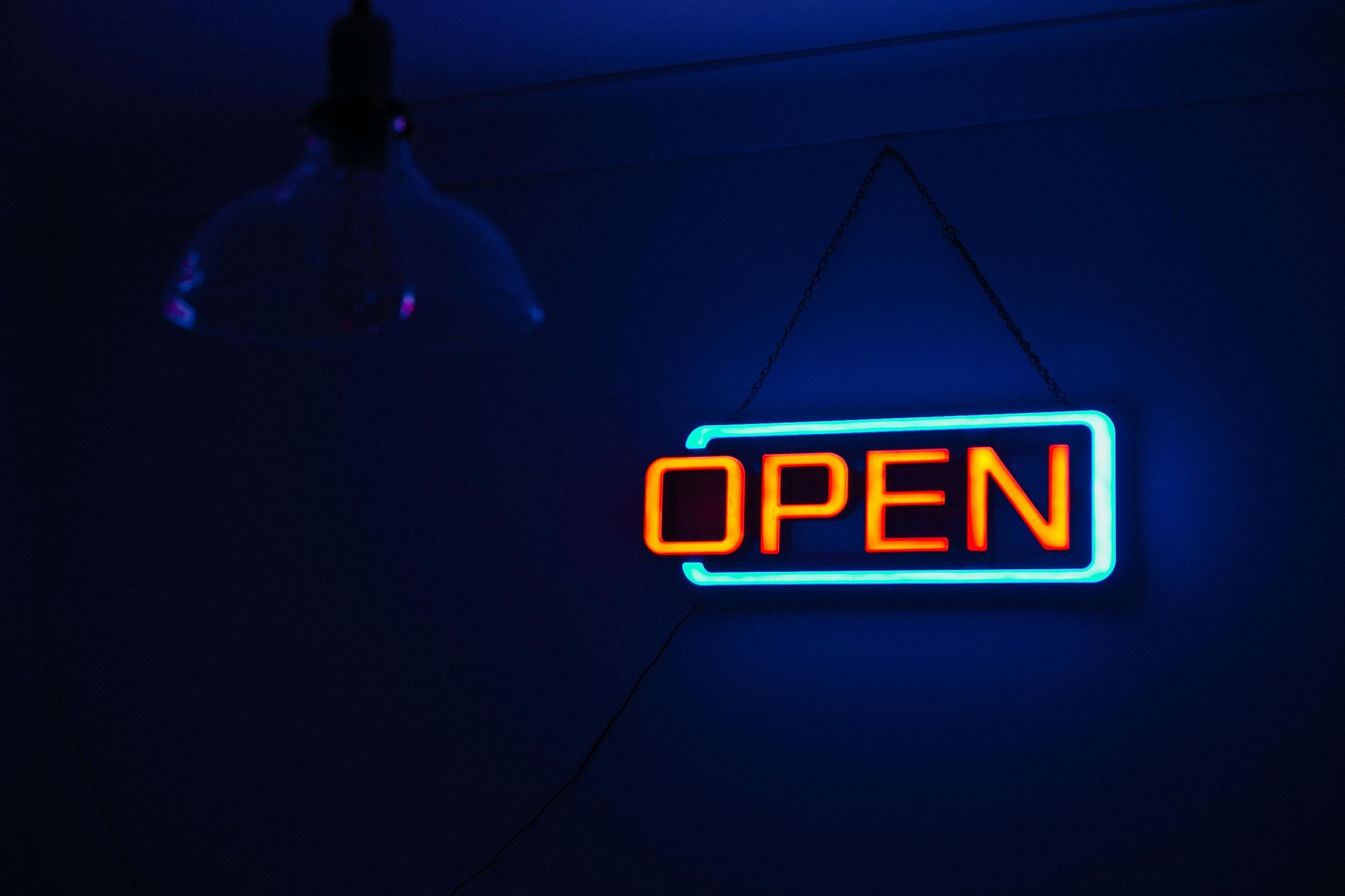 Neon open sign on a dark brick wall representing a new independent financial advisor firm launch.