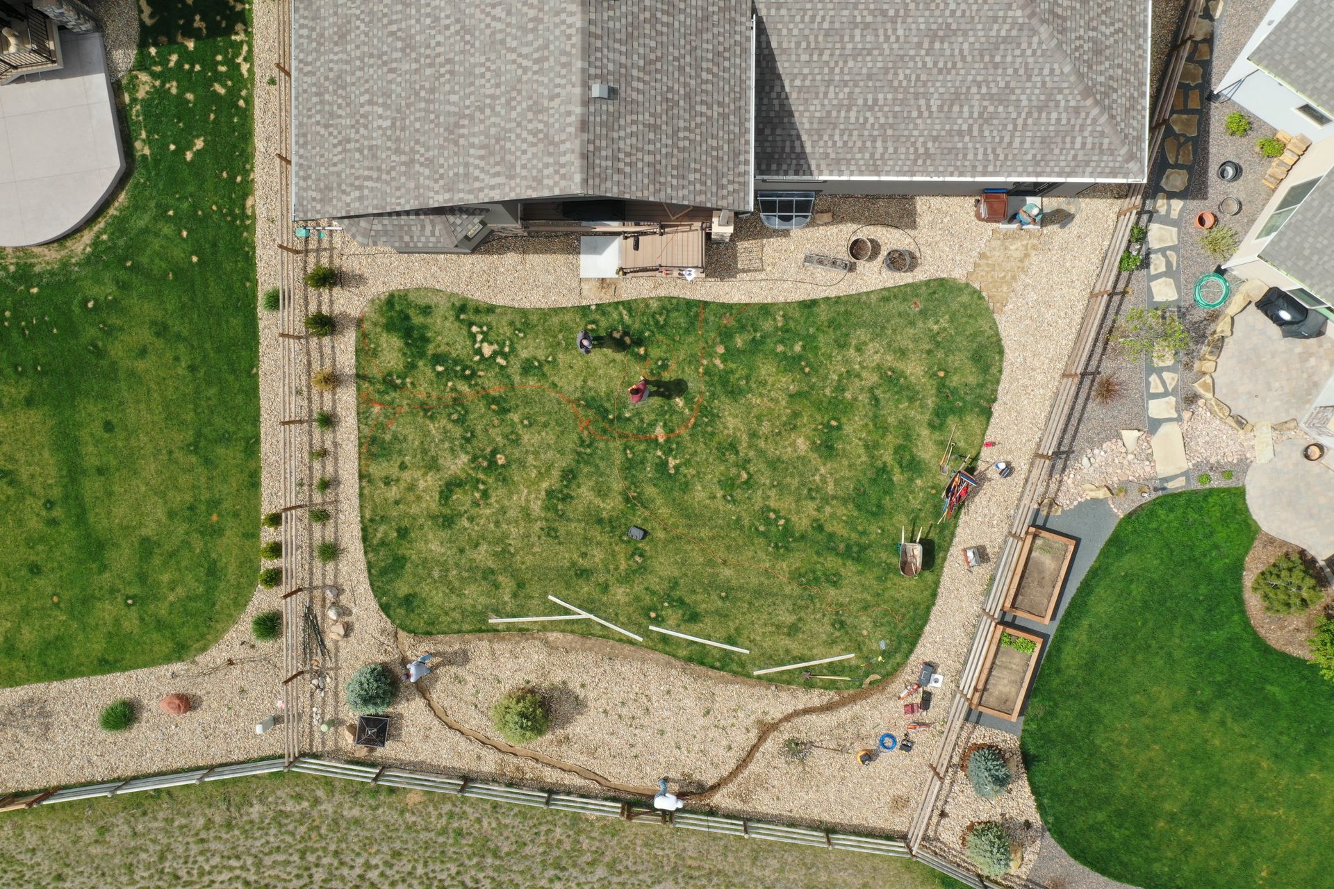 Aerial view of a backyard with grass, stone paths, and a house.