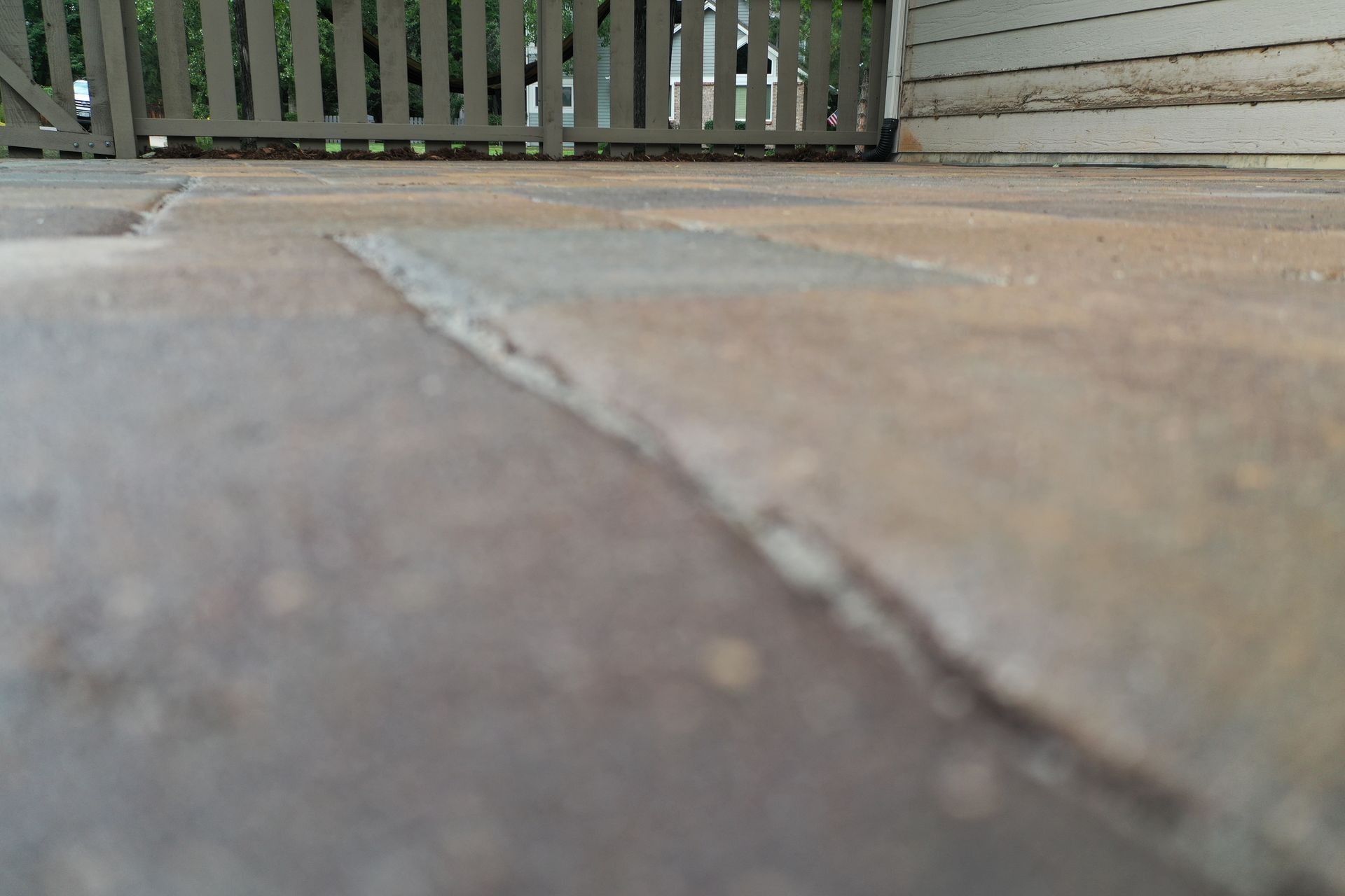 Close-up of brown paving stones leading to a wooden fence.