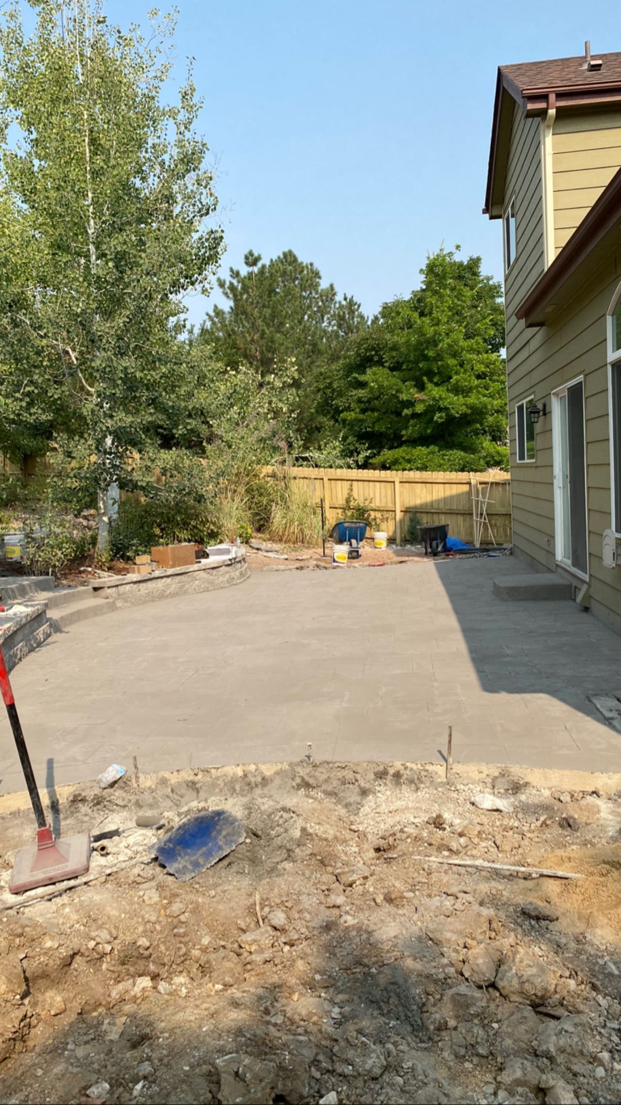 Newly poured concrete patio in a backyard setting, next to a house.