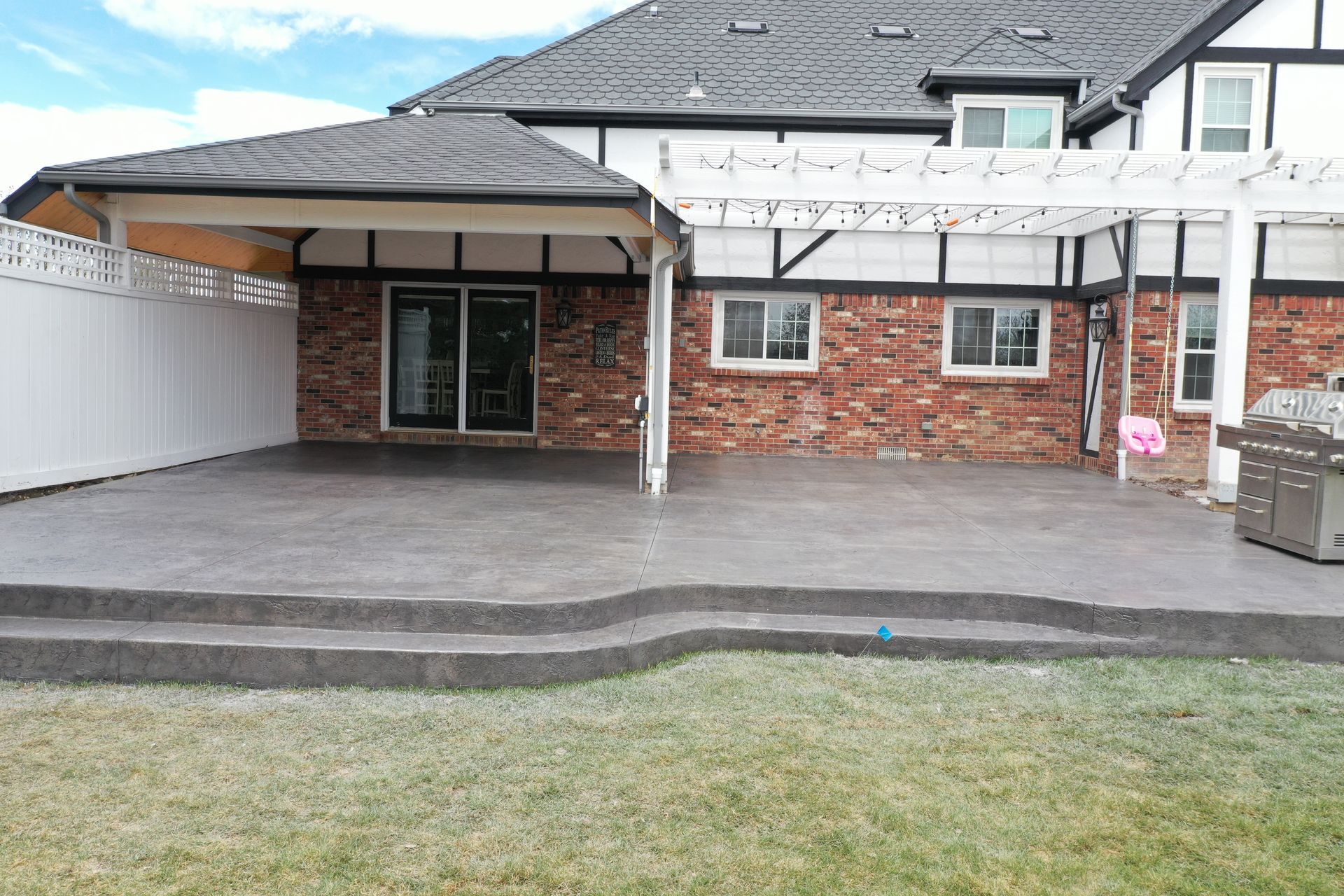 Backyard patio with steps, brick exterior, and covered area.