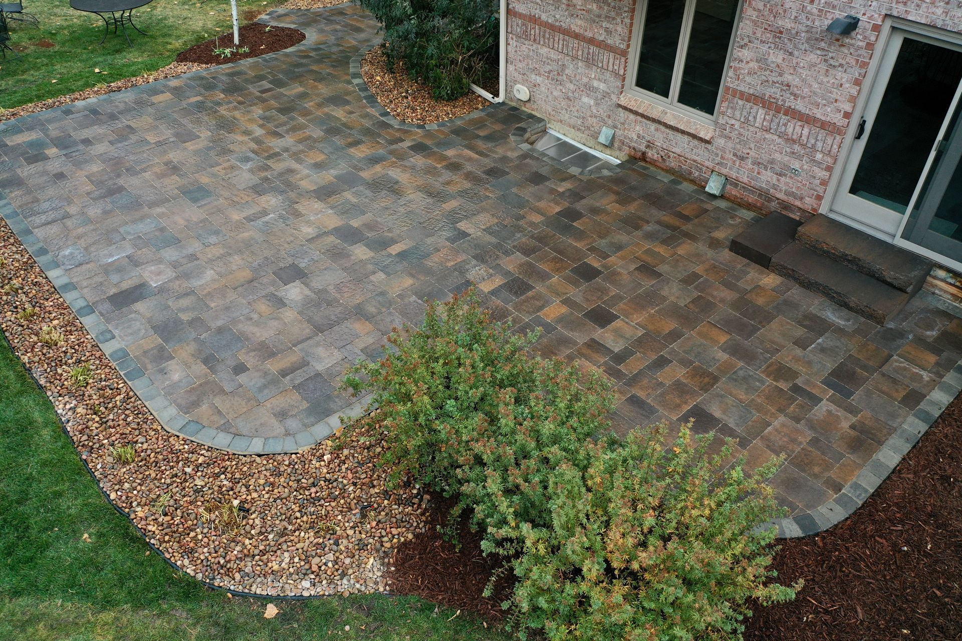 Brick patio with landscaping and brick house.