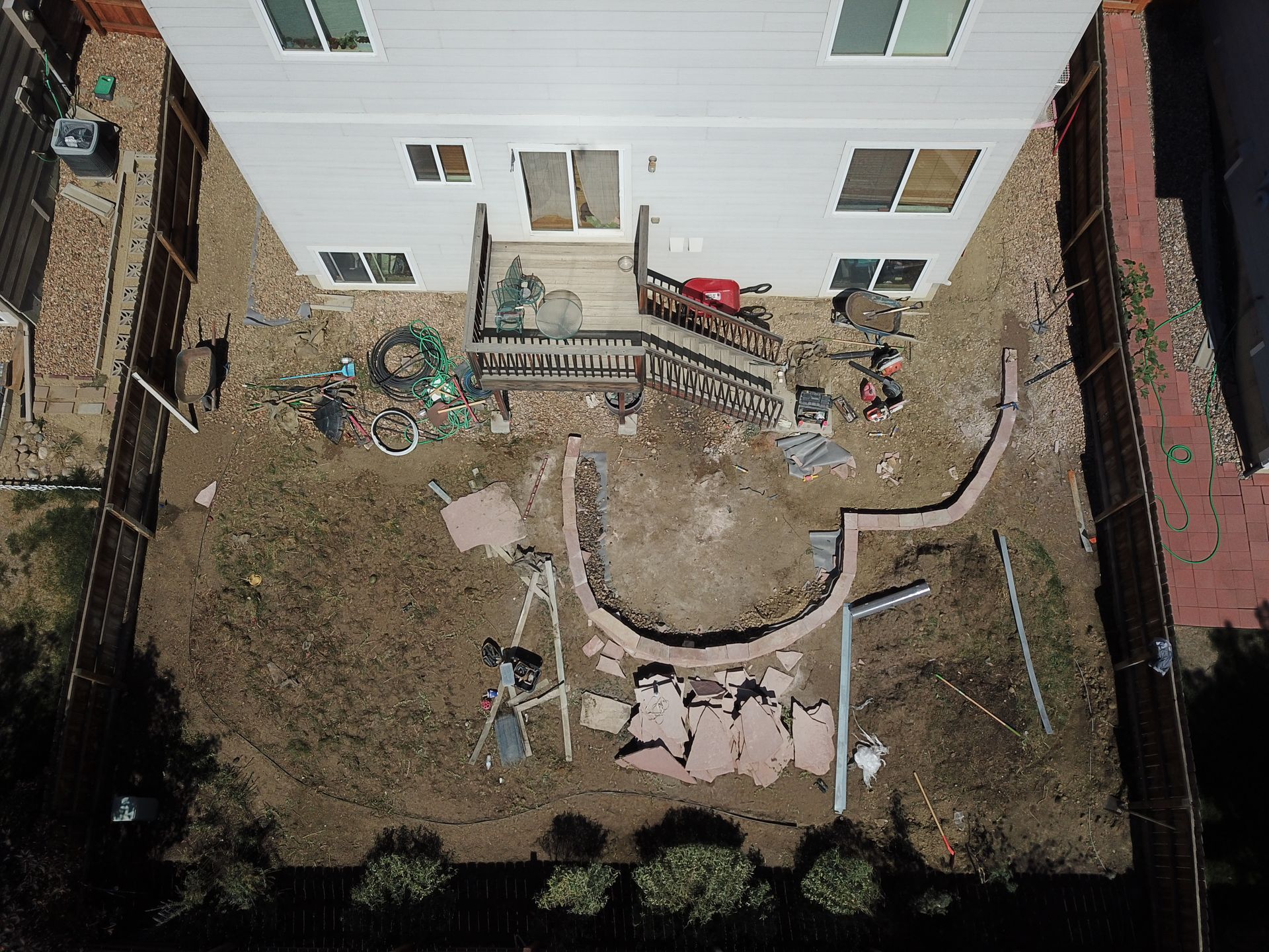 Backyard with a house, a curved wall, and construction debris.