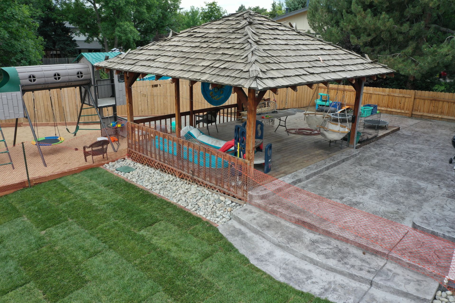 Backyard playground with a gazebo, swings, slides, and lush green lawn.