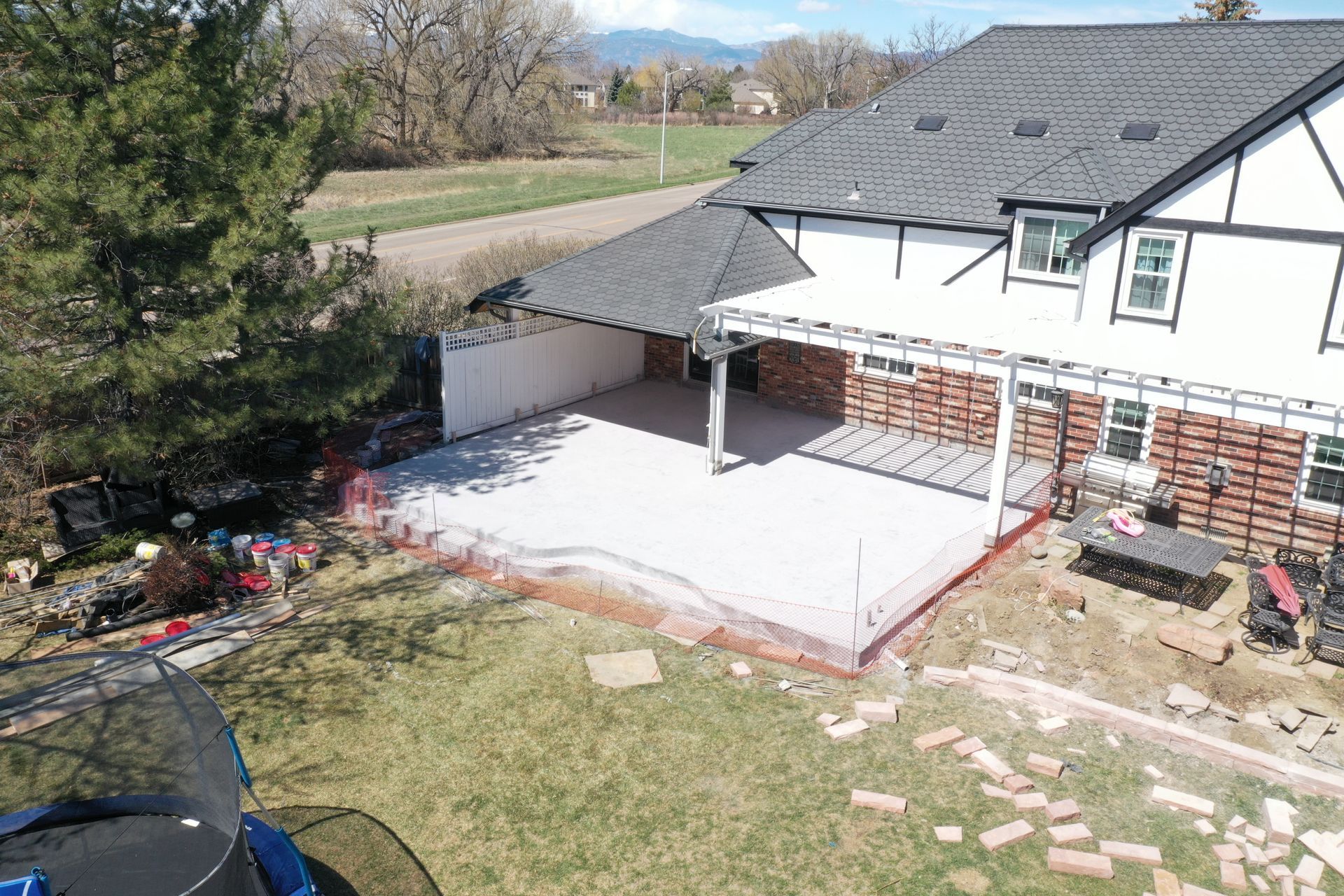 Backyard with a concrete patio under construction next to a house with a Tudor-style facade.