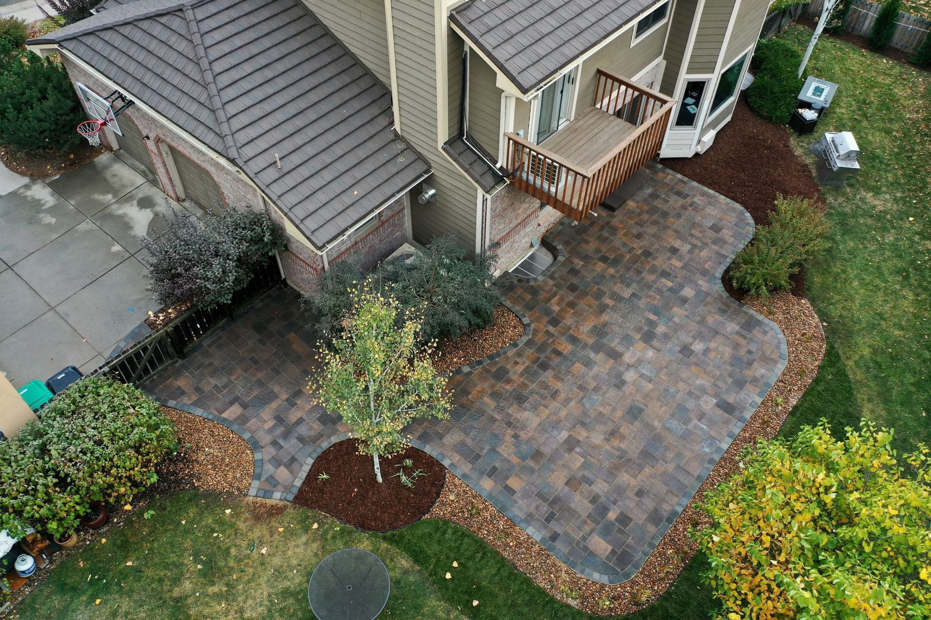 Overhead view of house with brick patio, small tree, and green lawn.