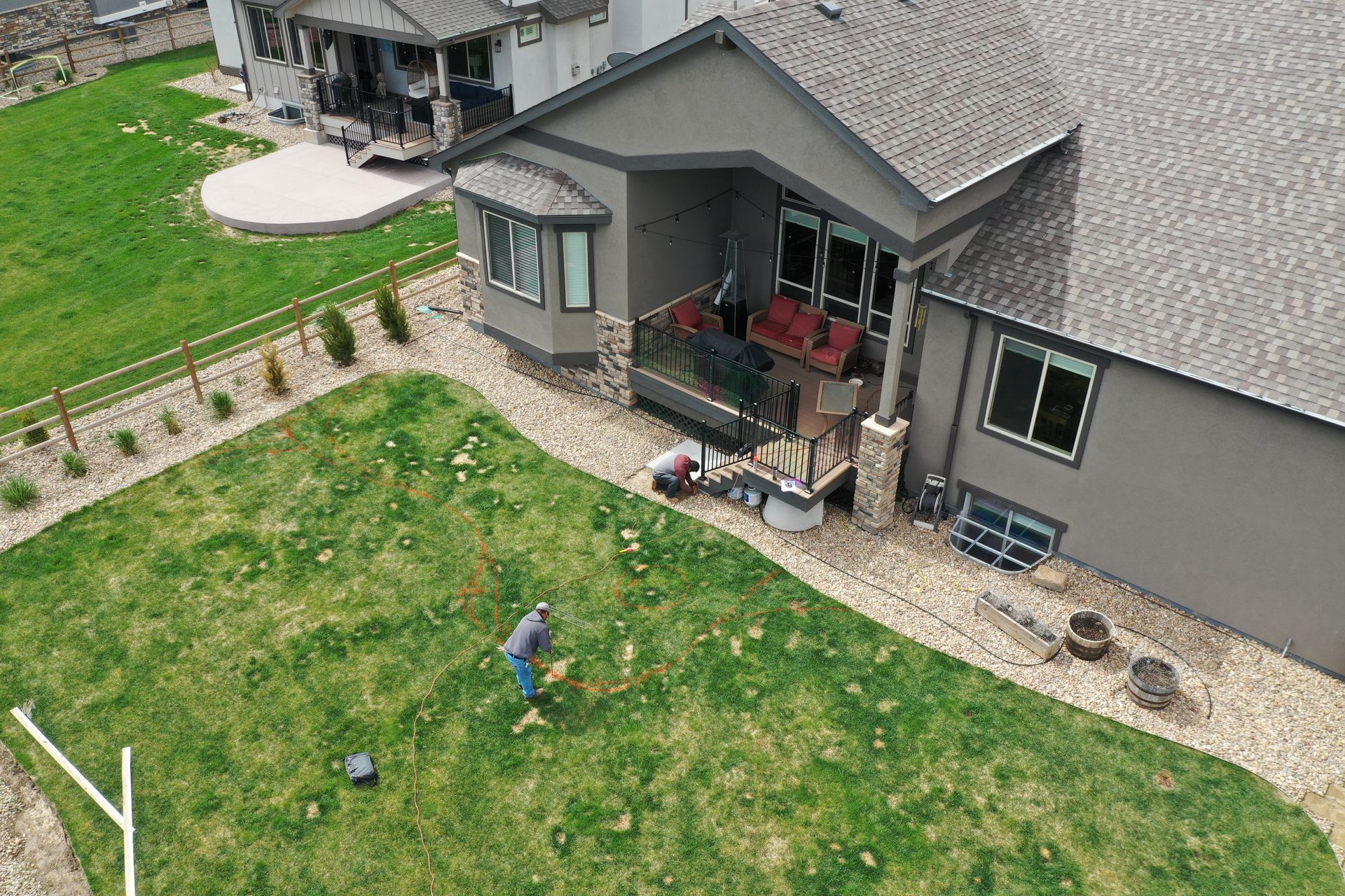 Aerial view of a home with a green lawn and a person working in the yard.