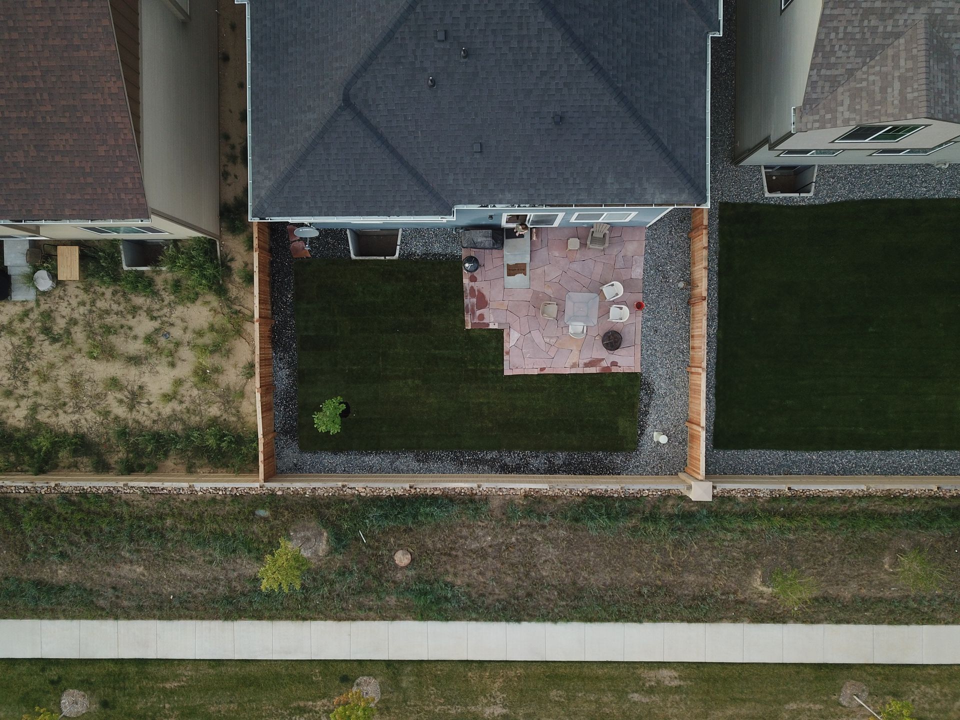 Overhead view of a house with a backyard patio surrounded by gravel and grass.