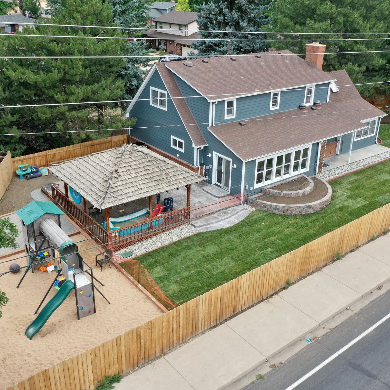 Blue house with wooden fence, patio, and a playset in the yard.