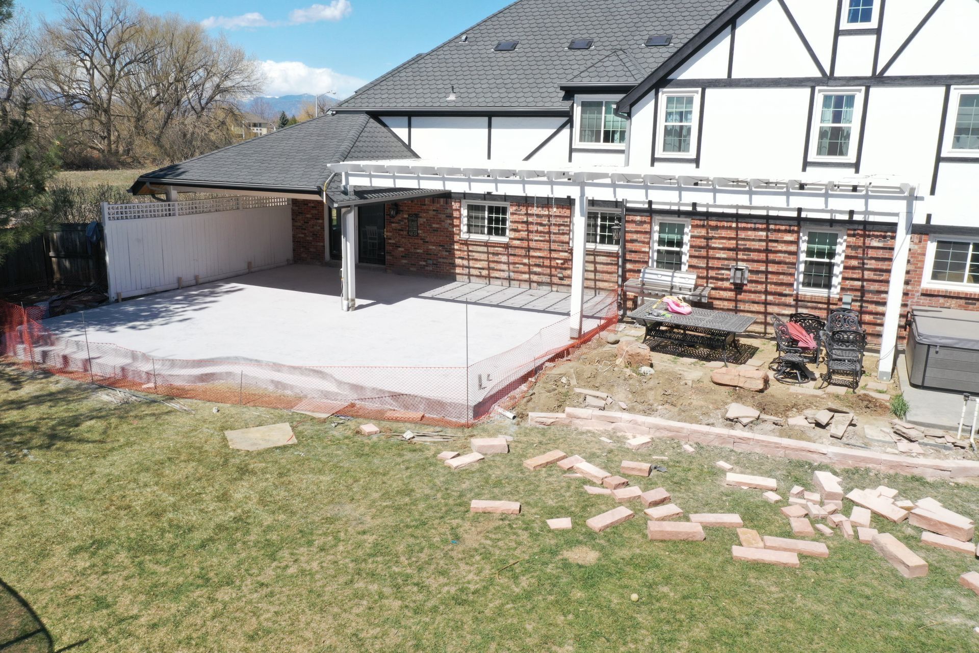 Backyard patio under construction with brick, exposed beams, and a house.