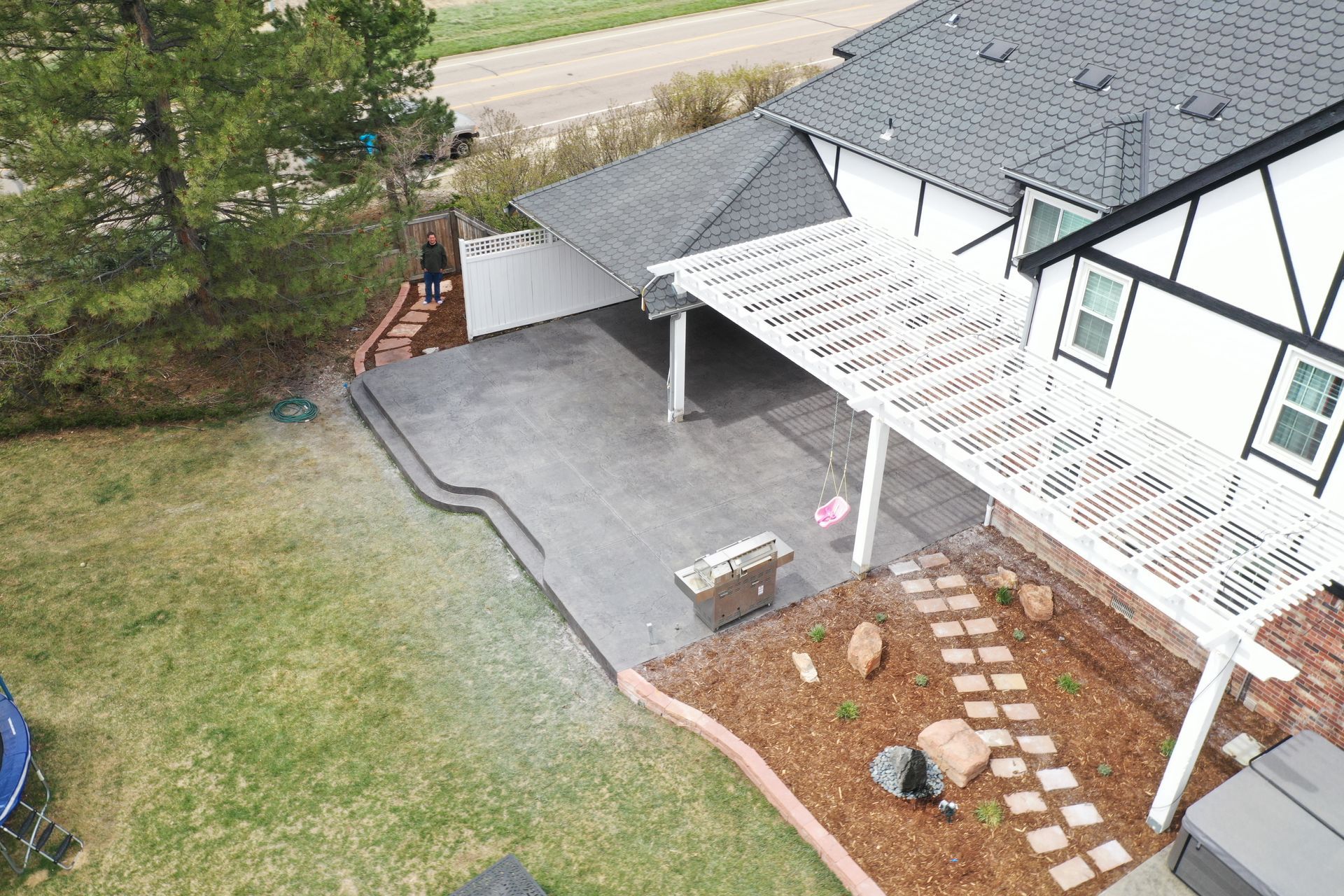Aerial view of backyard with a patio, pergola, and house with a Tudor-style exterior.