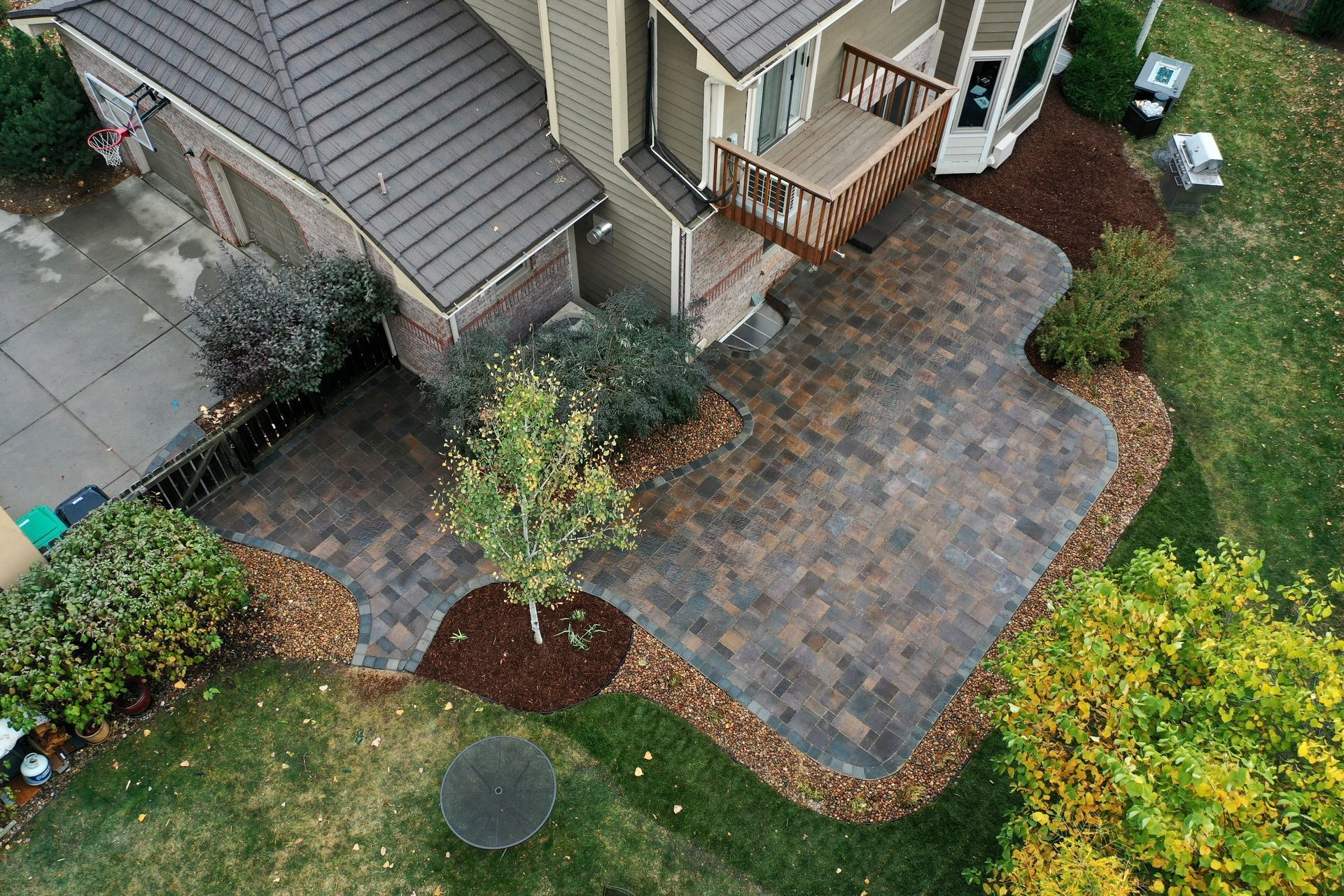 Aerial view of a home with a paver patio and a grassy yard.