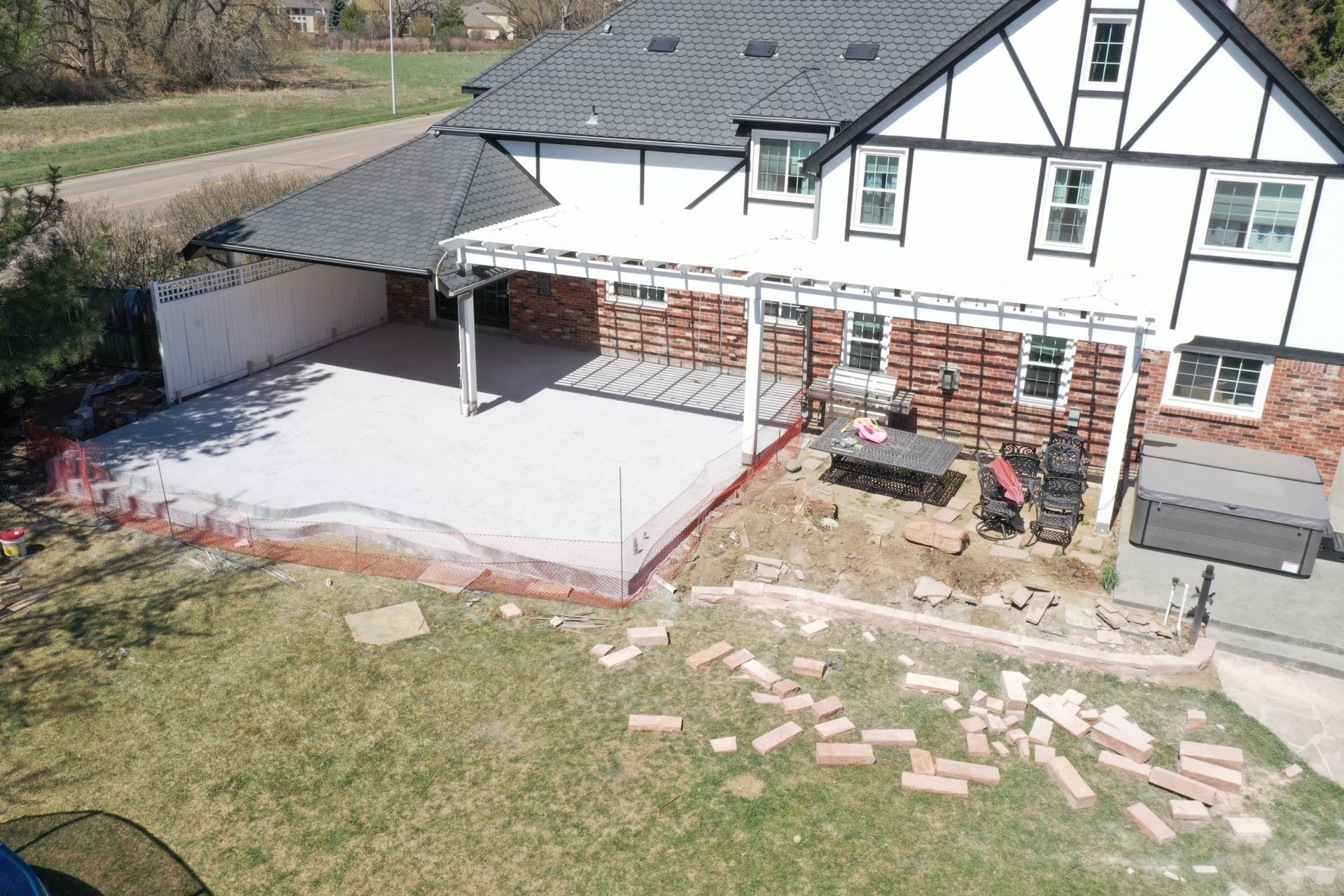 Backyard with a house under construction; exposed red brick, large concrete patio, and a lawn.