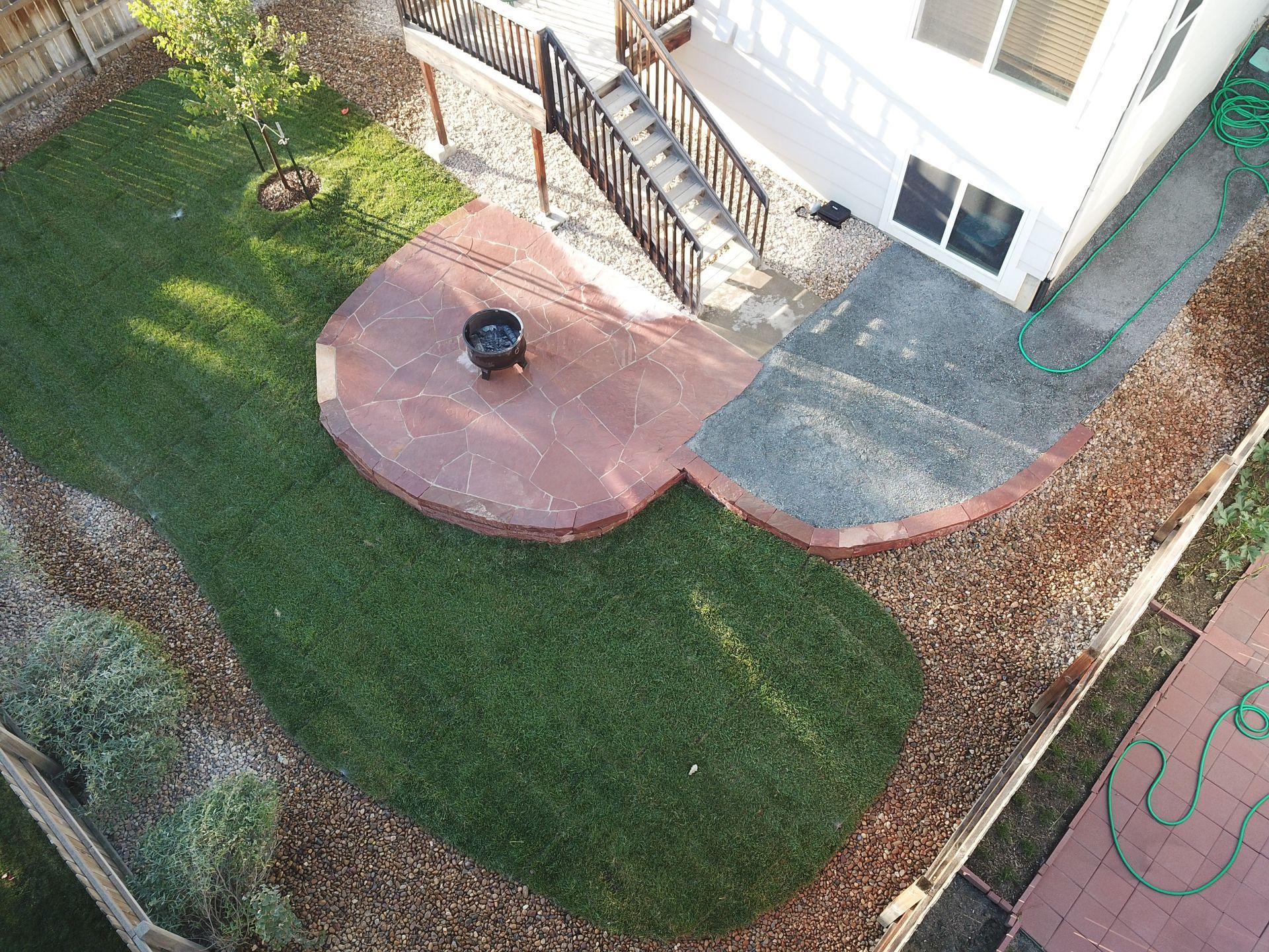 Overhead view of a backyard with a fire pit, grass, and a house.