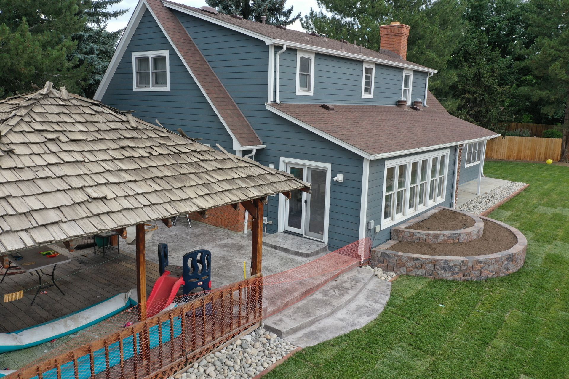 Blue house with a gazebo and patio in a grassy yard.
