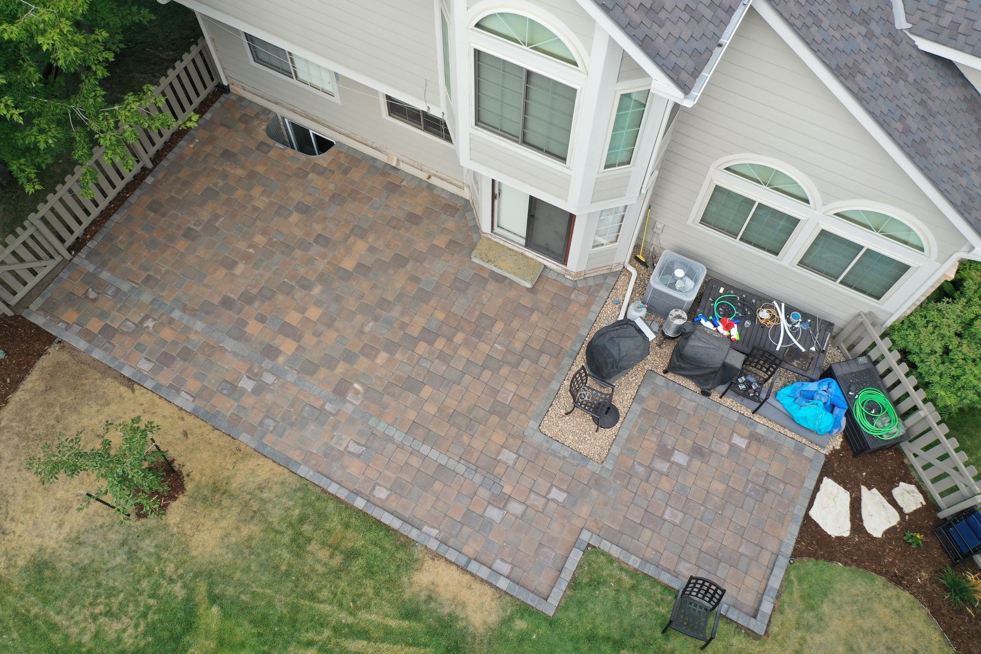 Overhead view of a brick patio next to a two-story house.