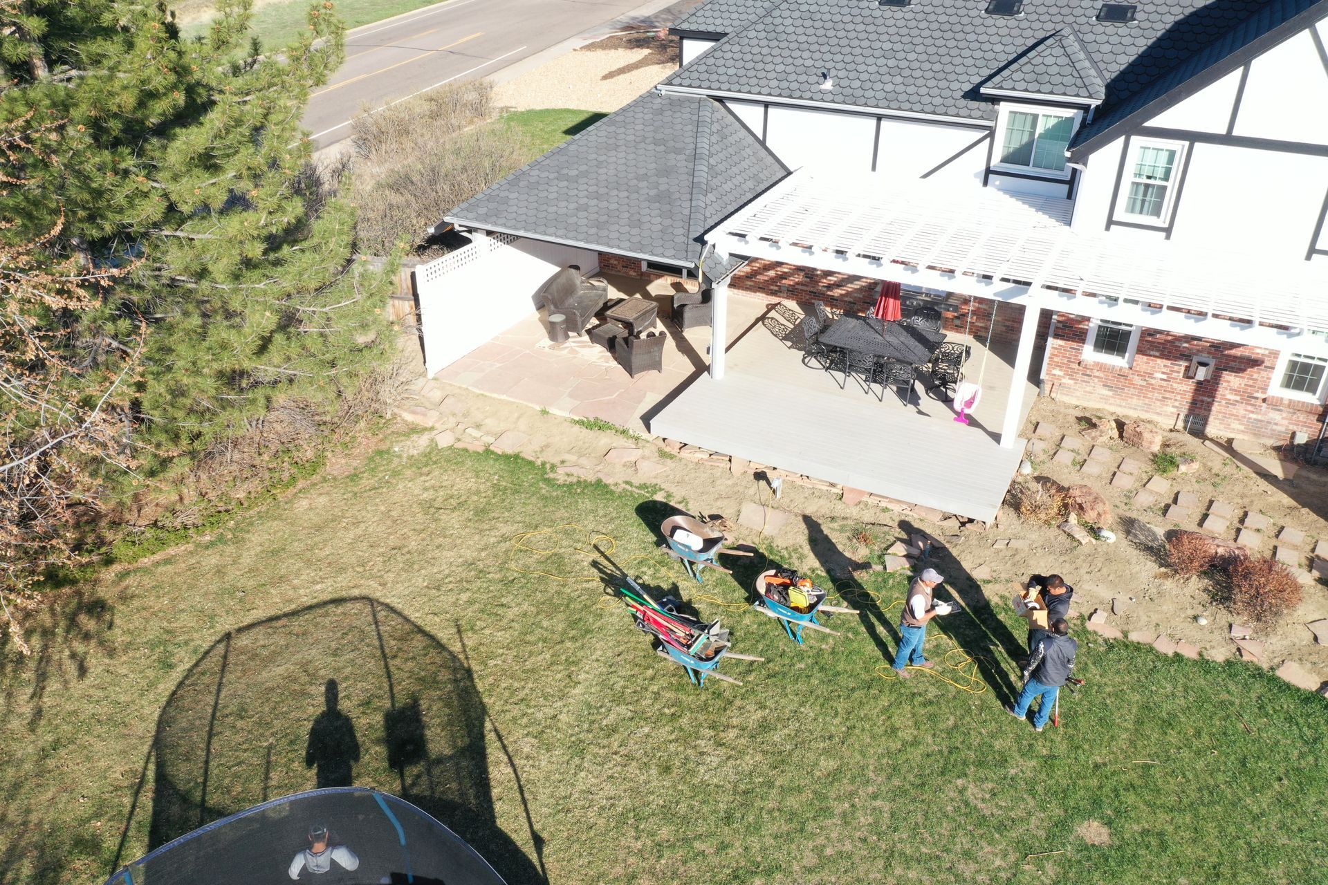 Aerial view: family on lawn near house with trampoline and patio.