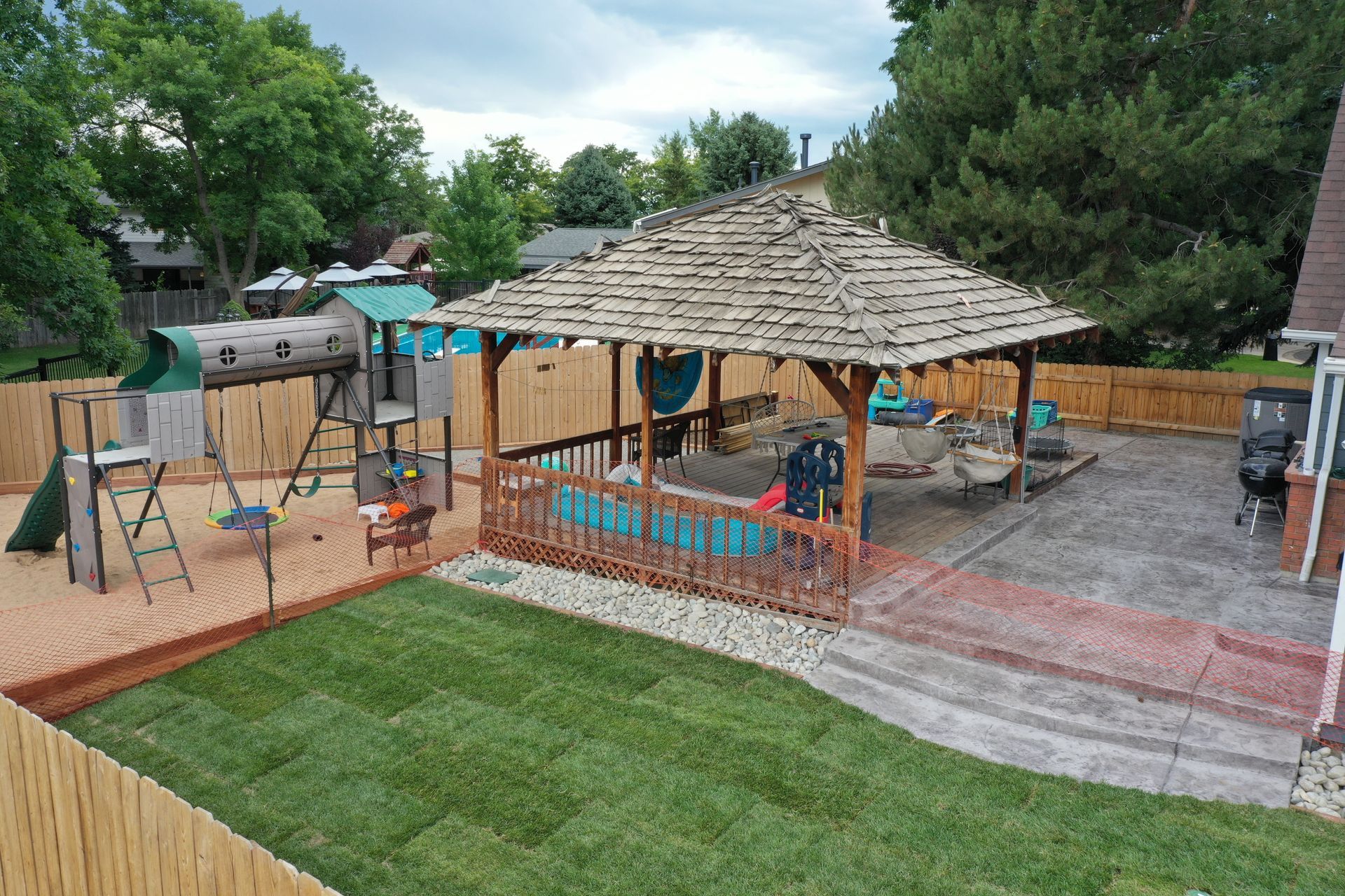 Backyard with playset, gazebo, new sod, and wooden fence.