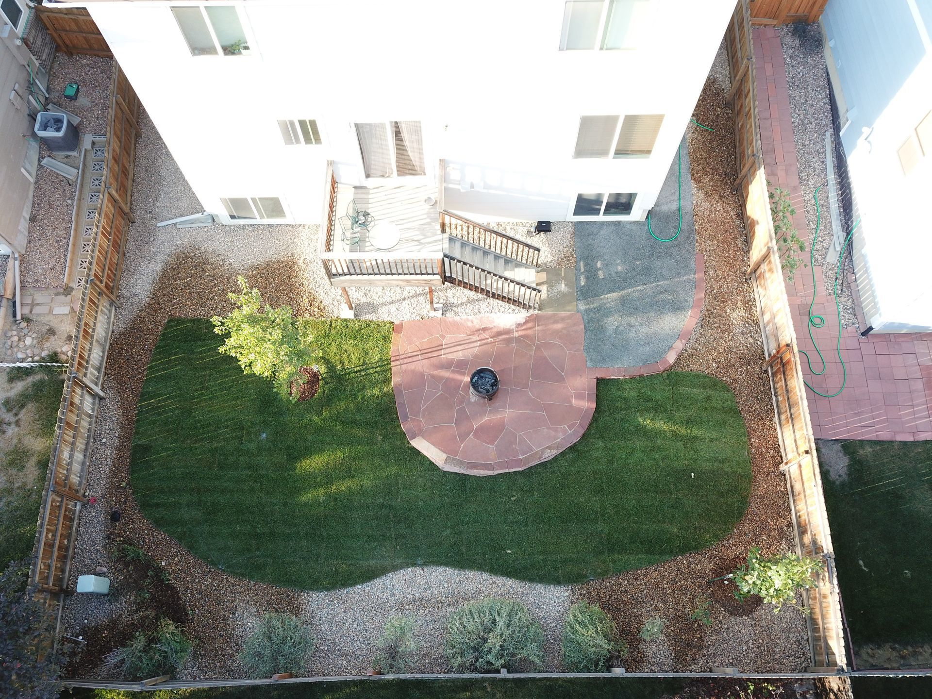 Overhead view of a backyard with a grass area, fire pit, and a house.