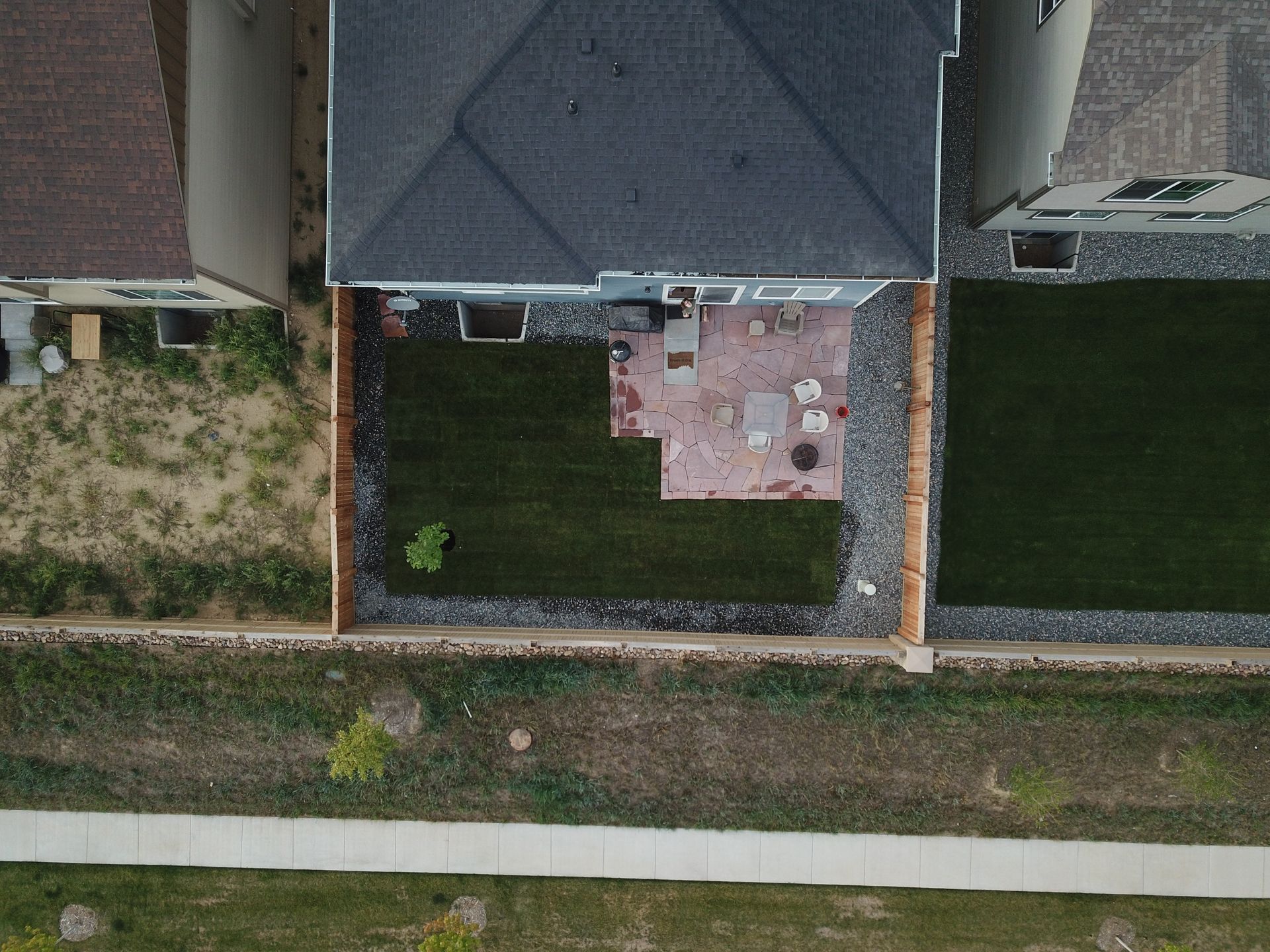 Overhead view of a house with backyard patio, surrounded by grass and rock borders.