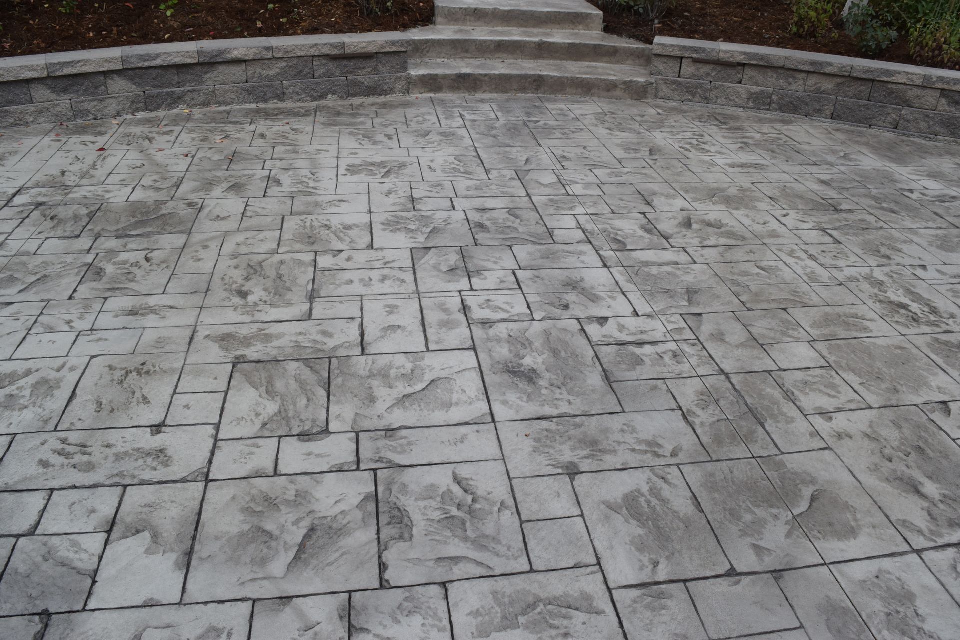 Stamped concrete driveway with a stone pattern leading to steps.