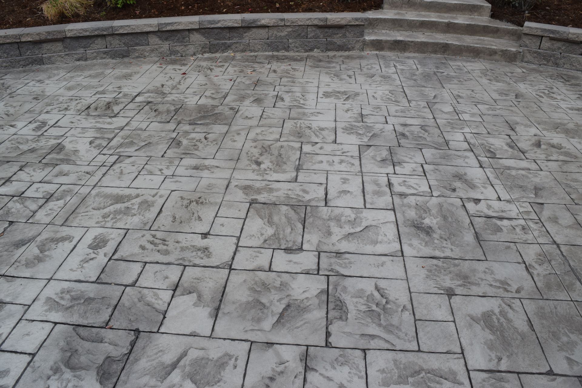 Stamped concrete patio with a stone pattern in shades of gray.