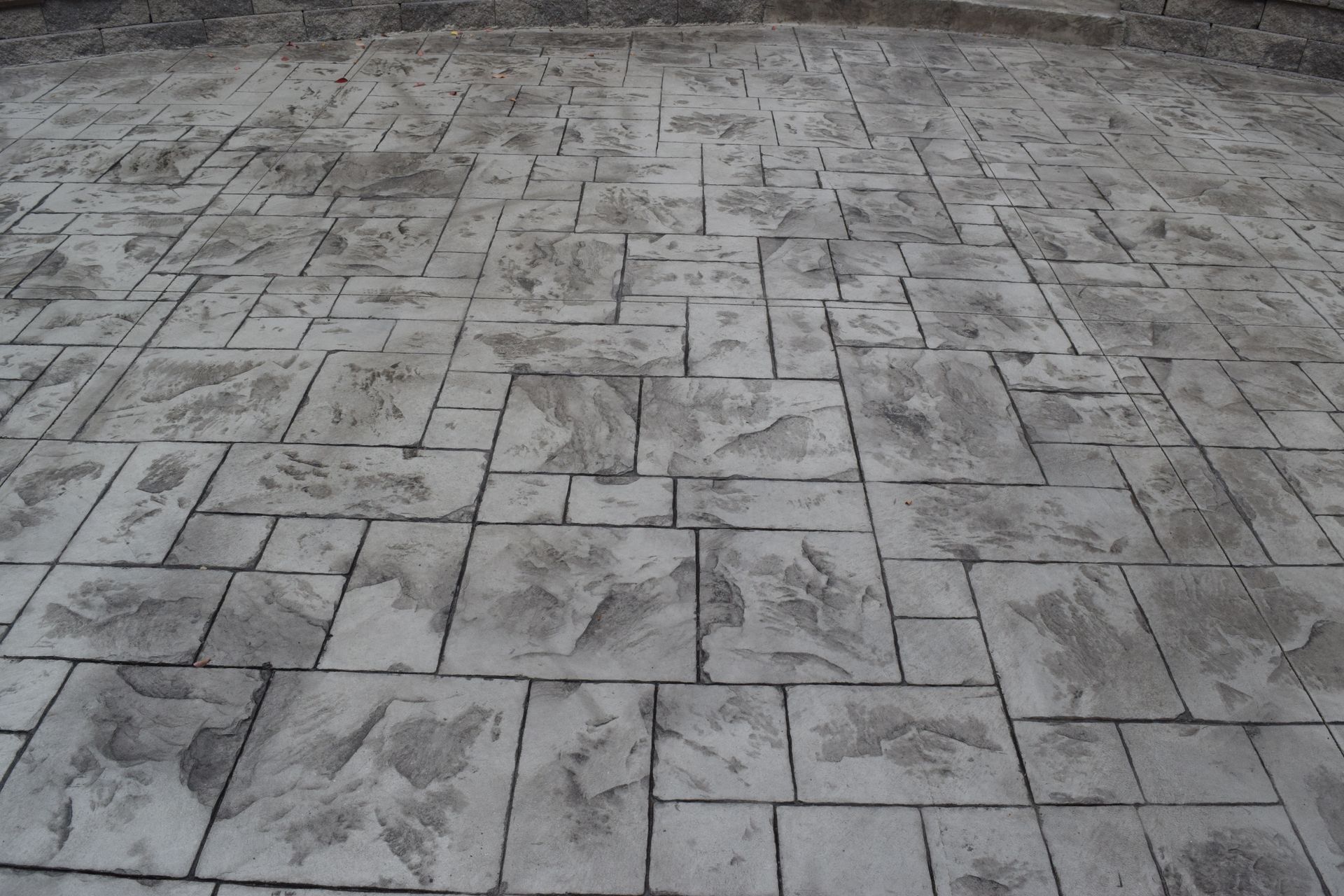 Gray stamped concrete patio with stone-like texture and irregular rectangular patterns.