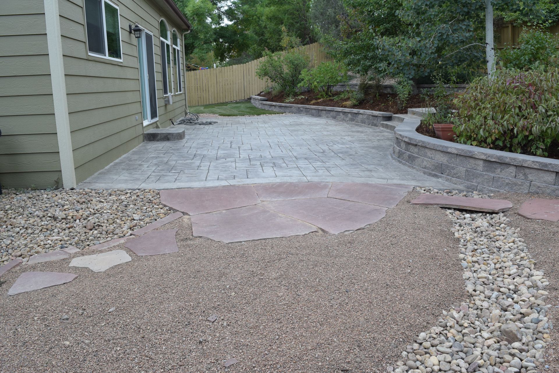 Backyard patio with stamped concrete, rock garden, and retaining wall.