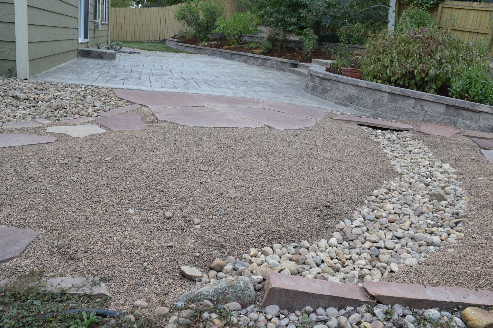 Gravel and stone landscaping with a flagstone path leading to a paved patio.