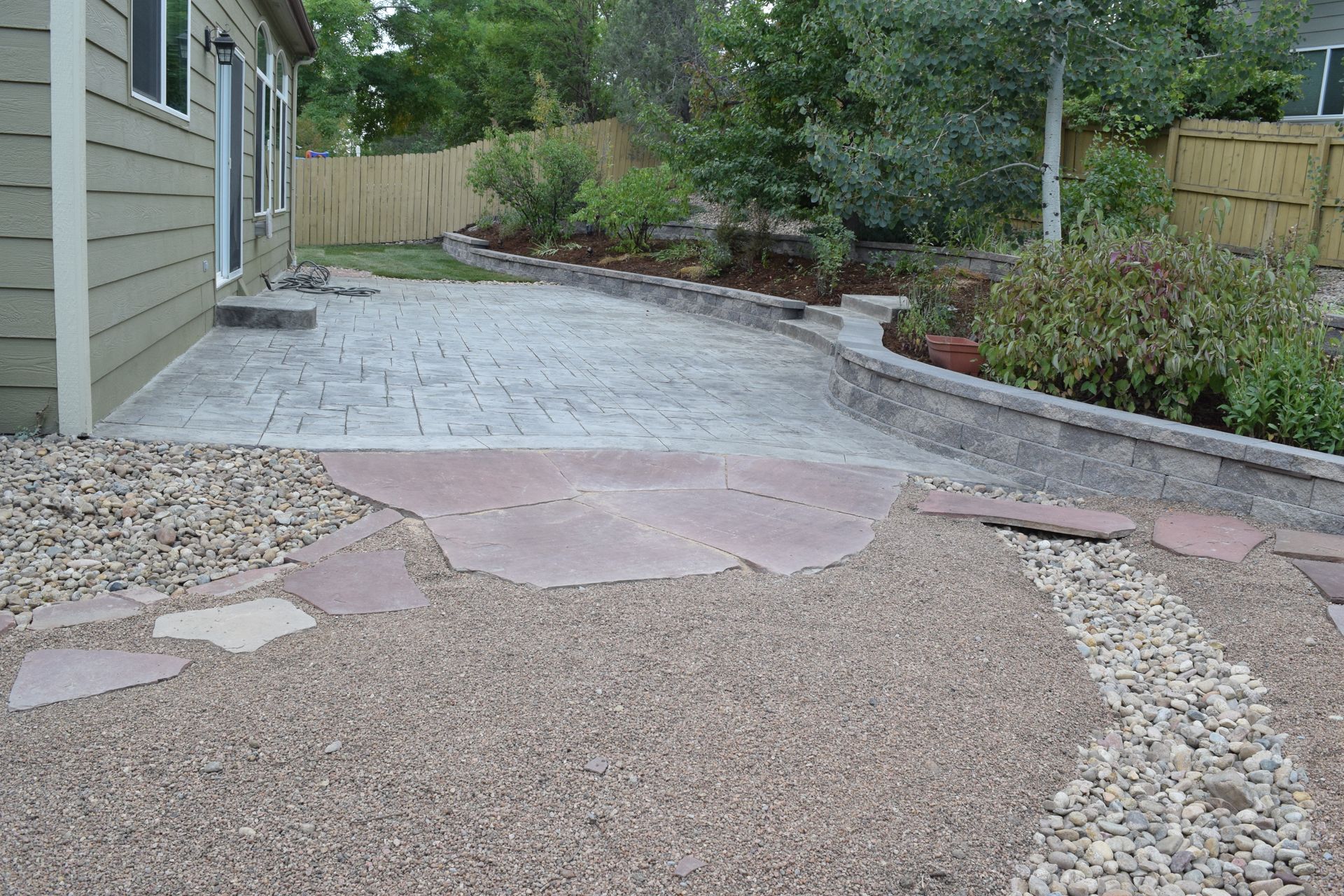 Backyard patio with gravel, flagstone path, and stamped concrete.