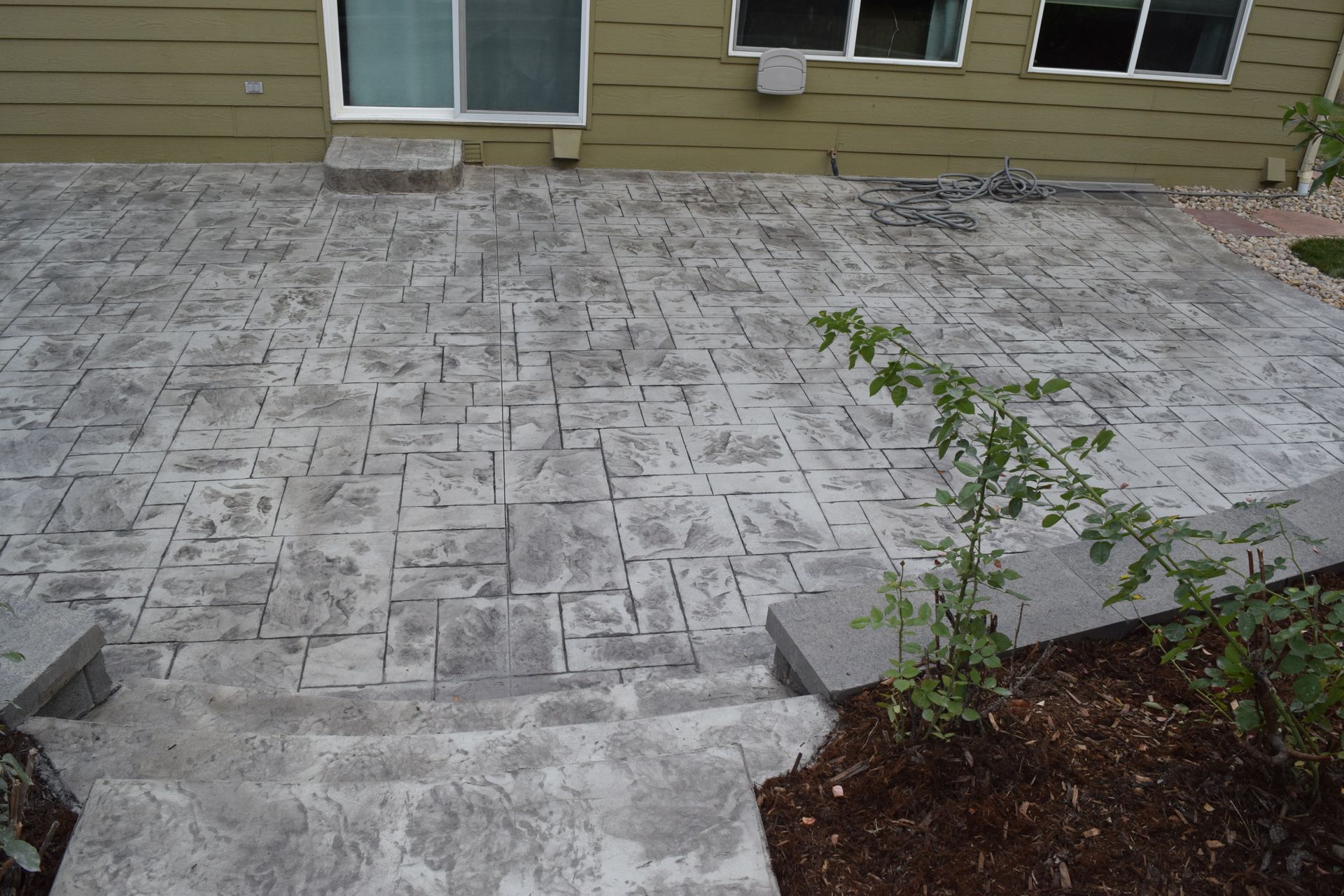 Concrete patio with patterned surface, steps leading down, near a building.