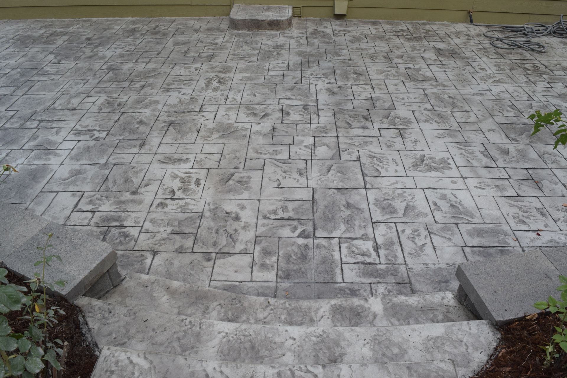 Stamped concrete patio with steps and a block pattern.