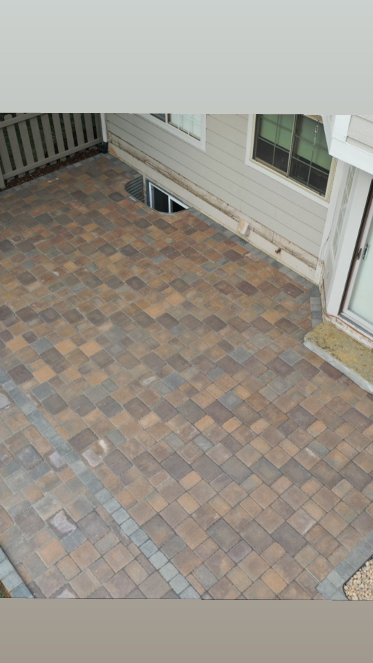 Brick patio next to a house with a door and windows.