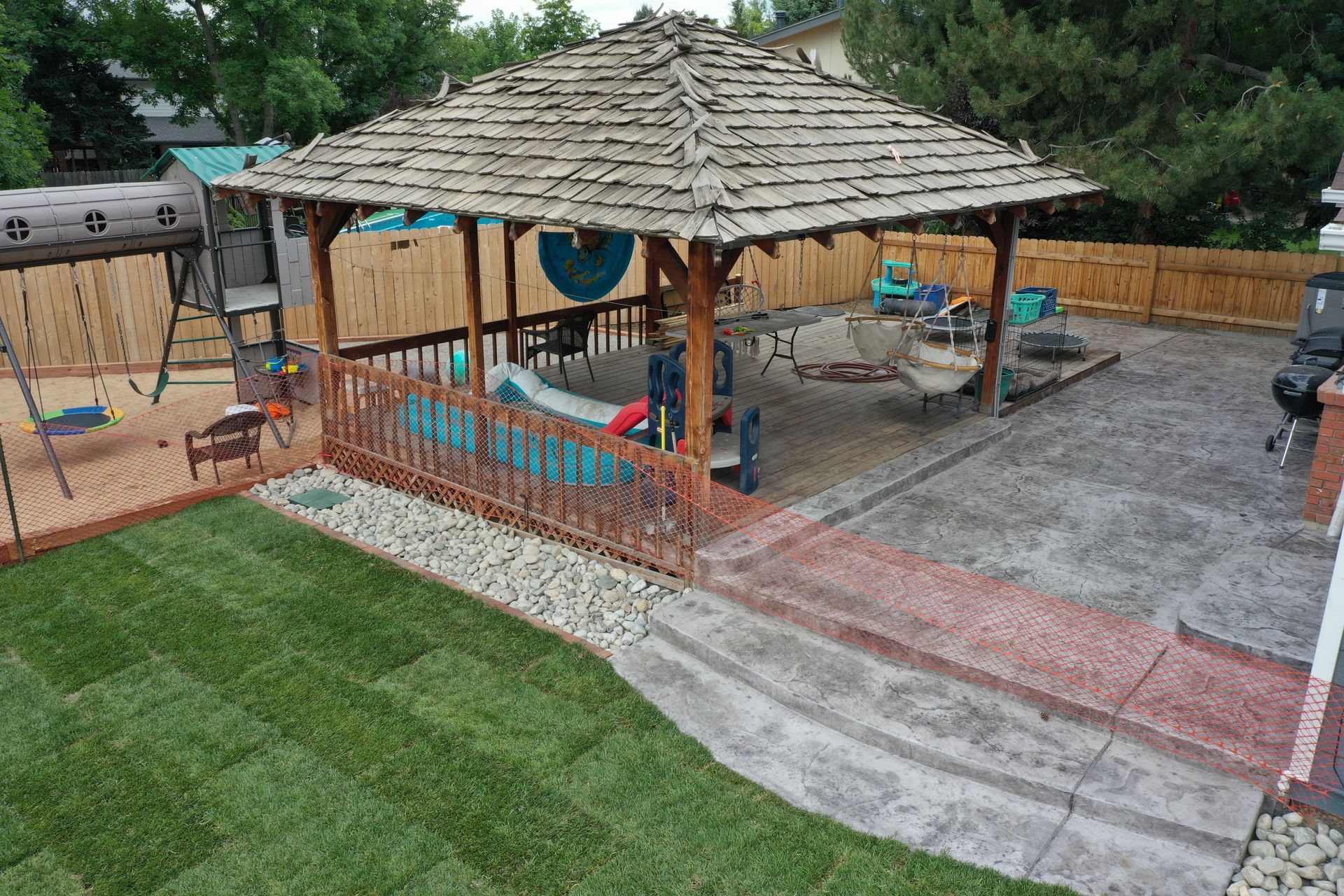 Backyard with gazebo, play set, patio furniture, and newly laid green grass.