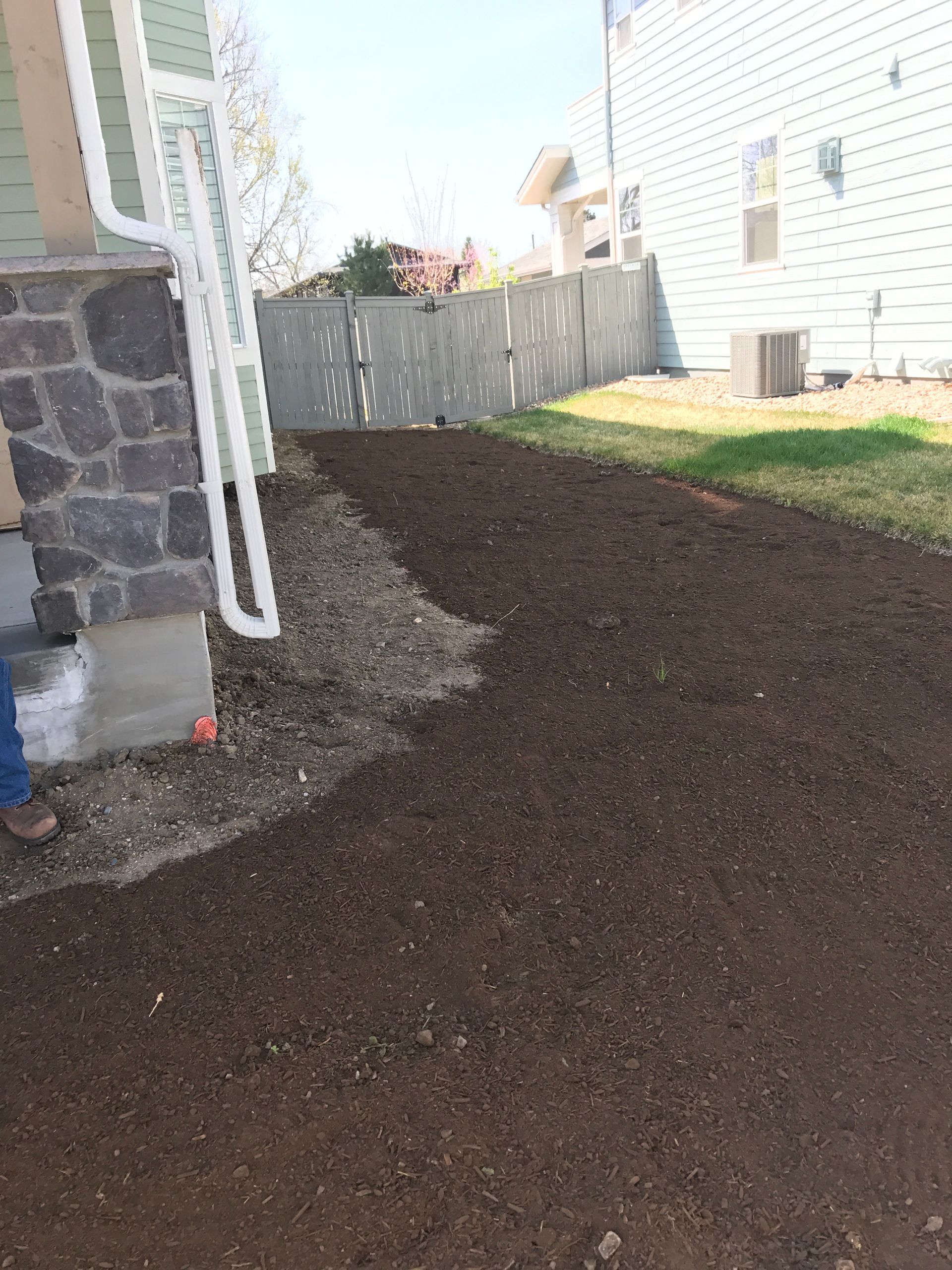 Dirt path next to a building, along a fence.