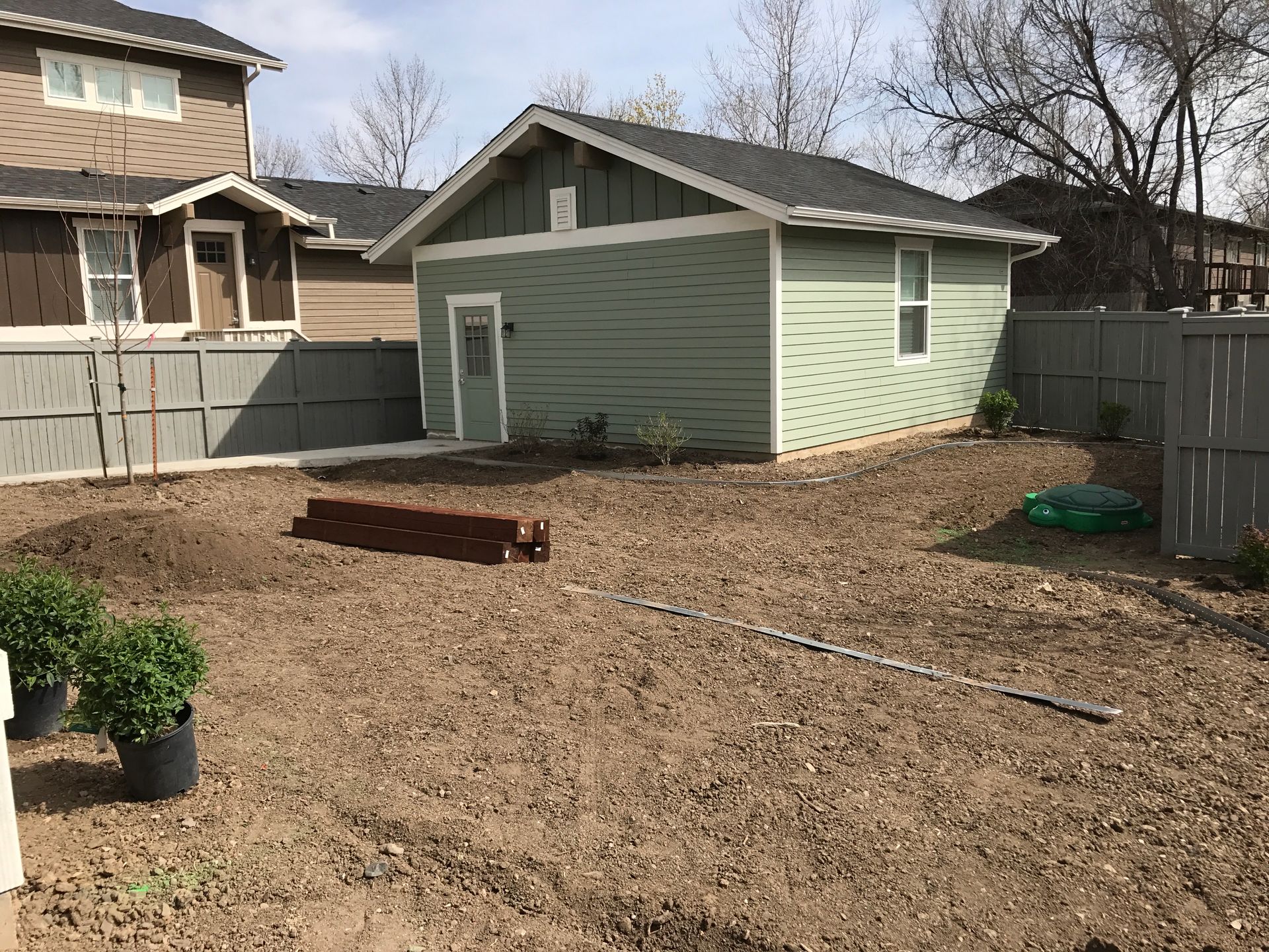 Backyard with a green shed, fence, and bare ground, ready for planting.